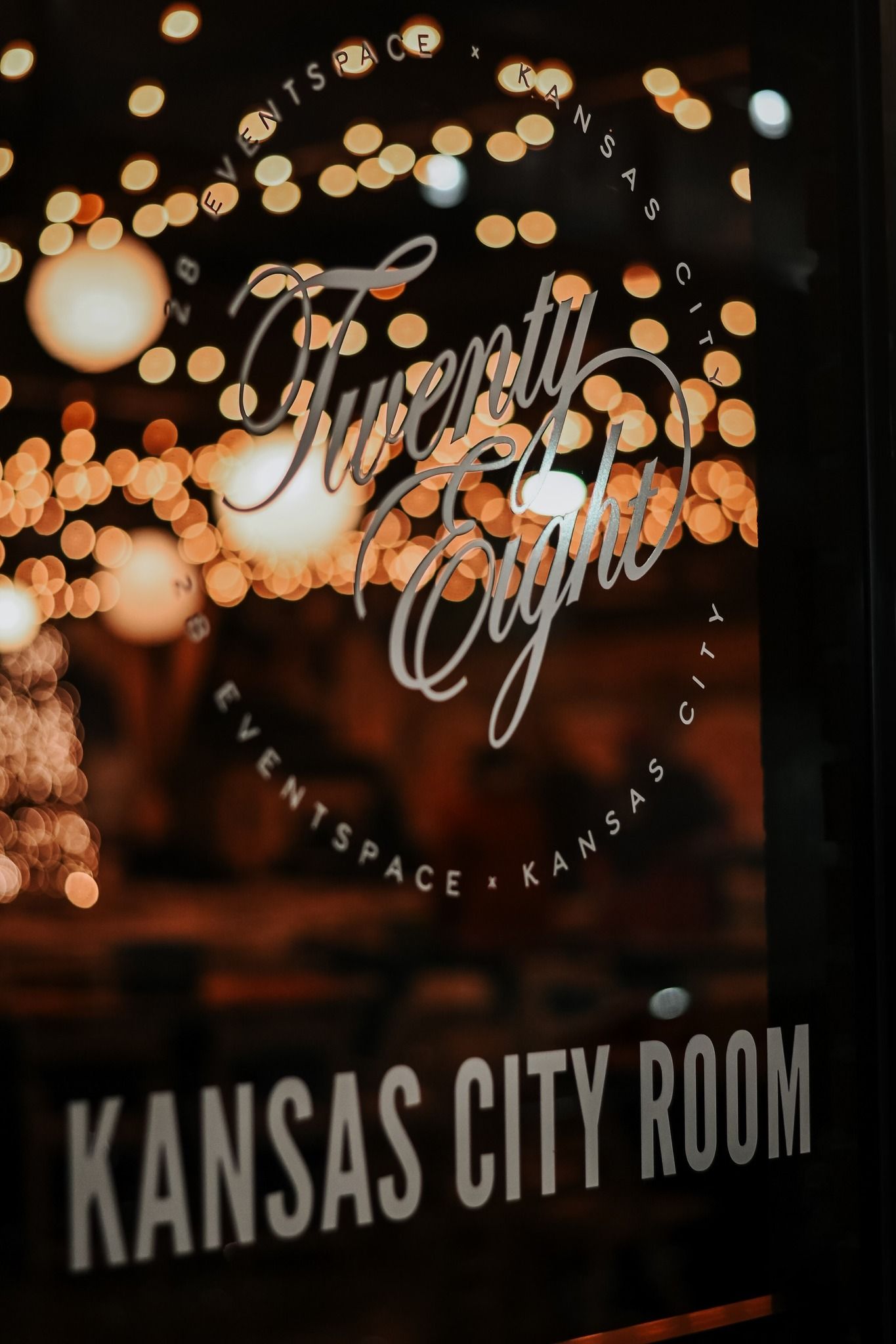 Twenty Eight Event Space Kansas City Room entrance sign with warm bokeh string lights background.