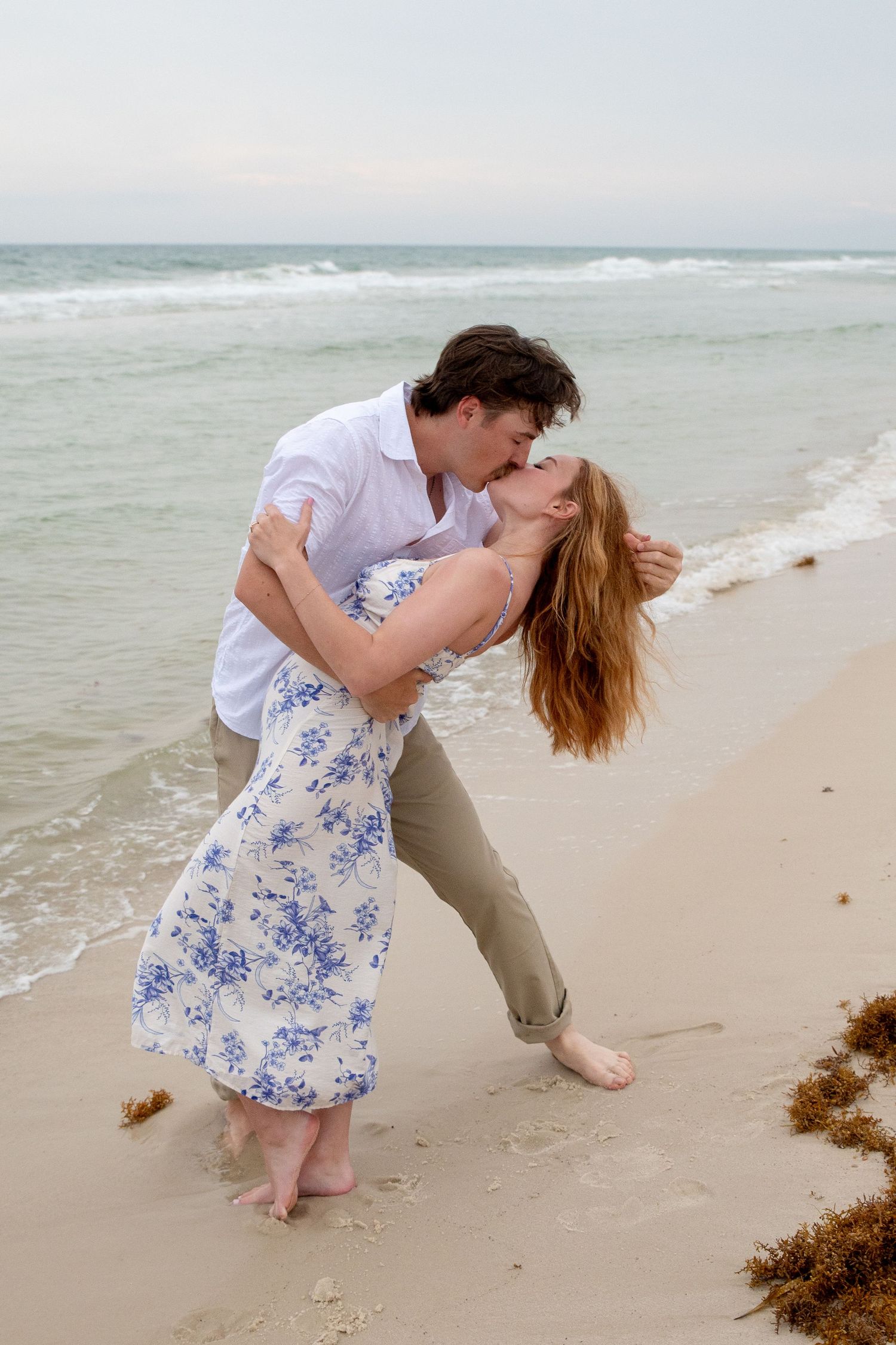 Emotional proposal moment on the beach with waves gently crashing in the background