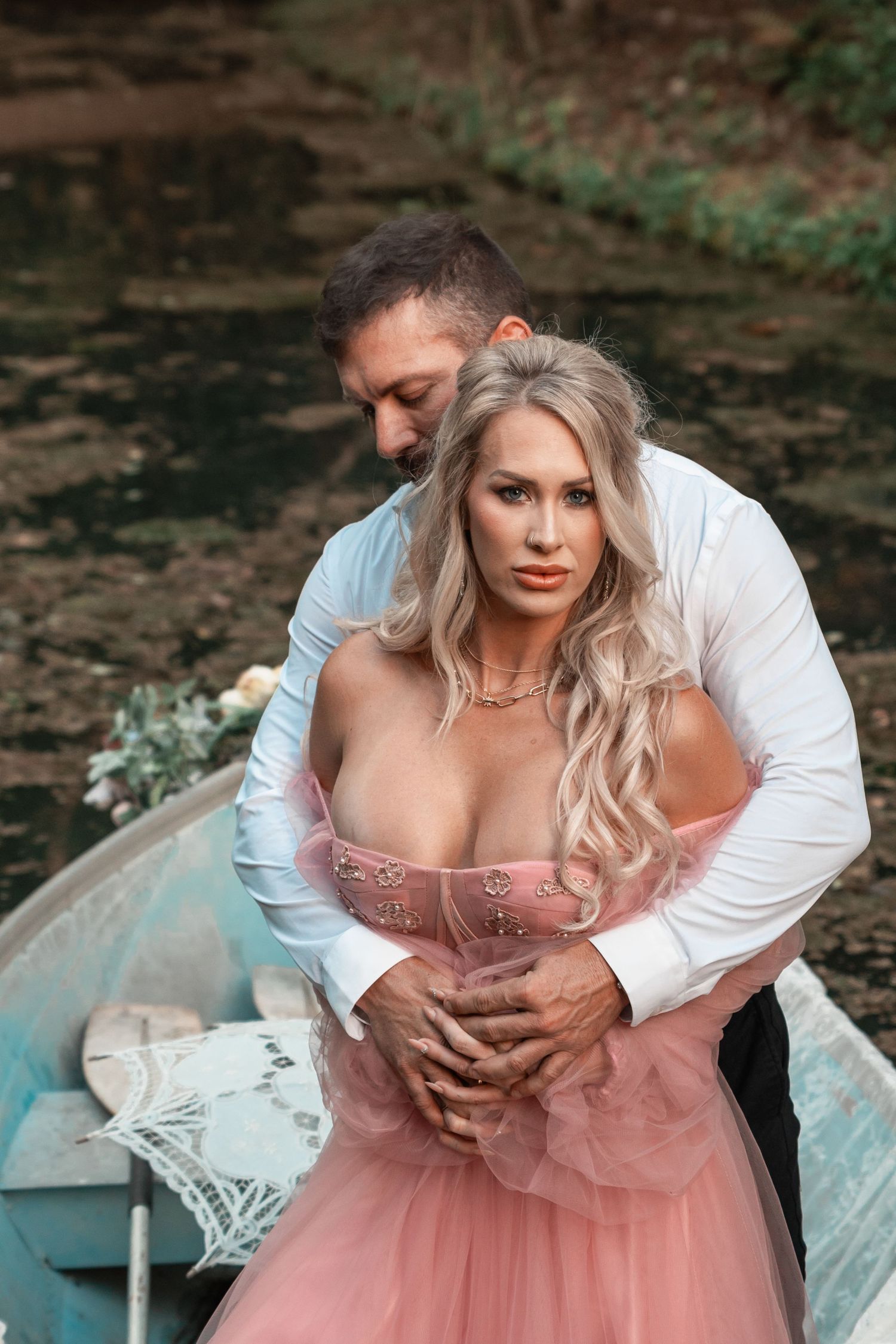 Moody couples portrait on a vintage-style boat with flowing dress and golden light
