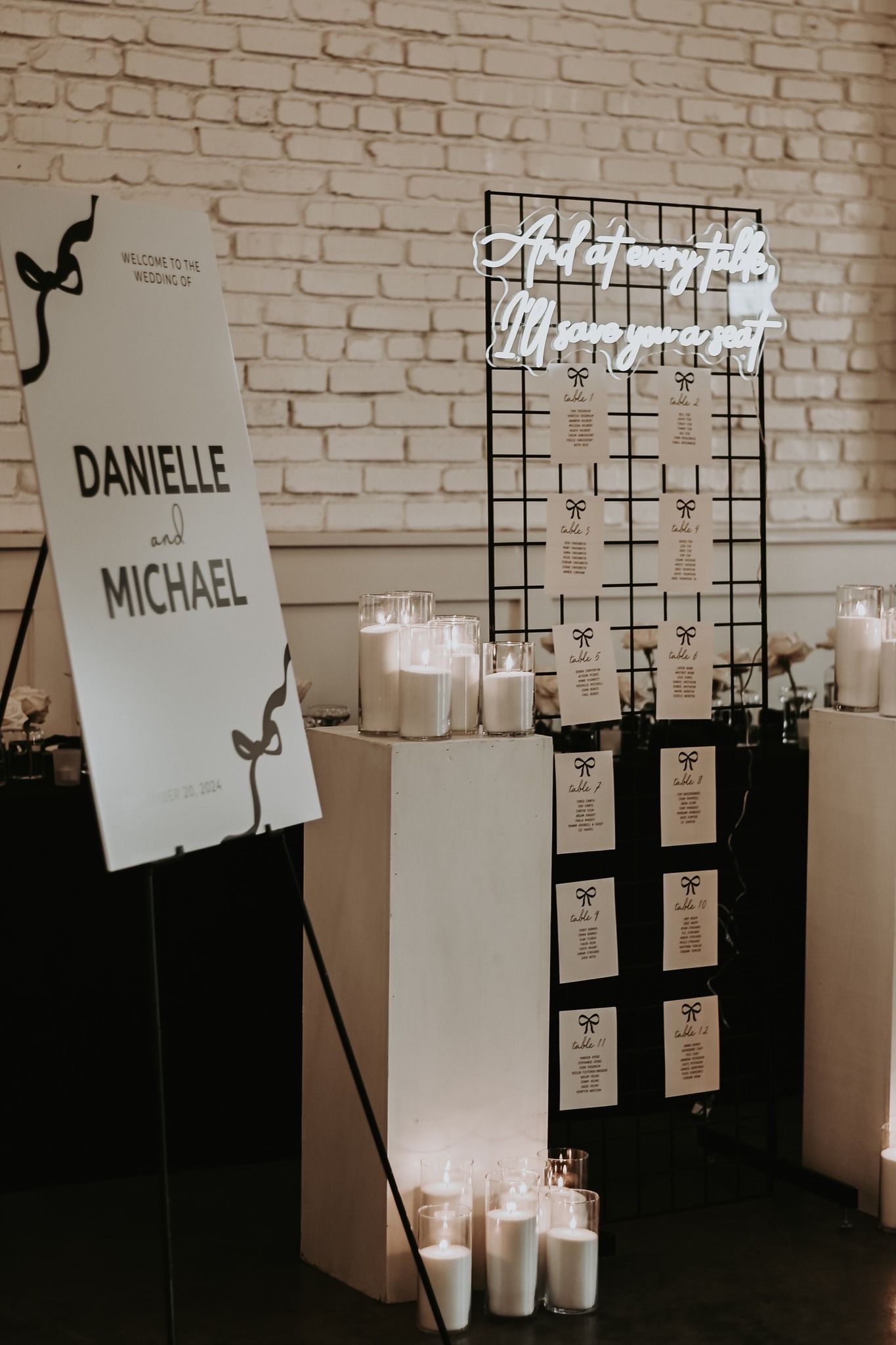 Wedding welcome display for Danielle and Michael with neon seating chart sign and white candles.