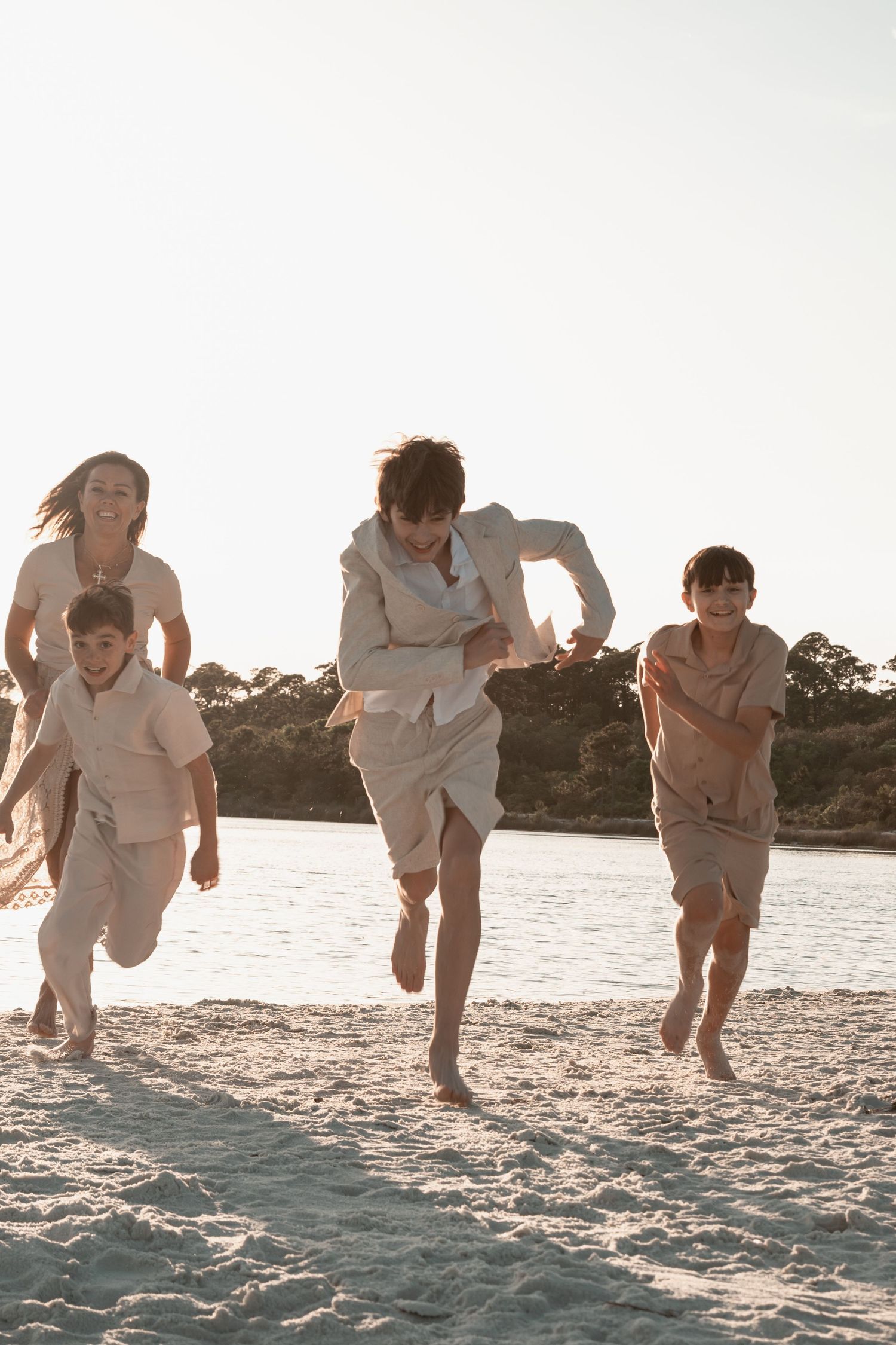 Happy family playing and running along shoreline during golden hour beach sunset