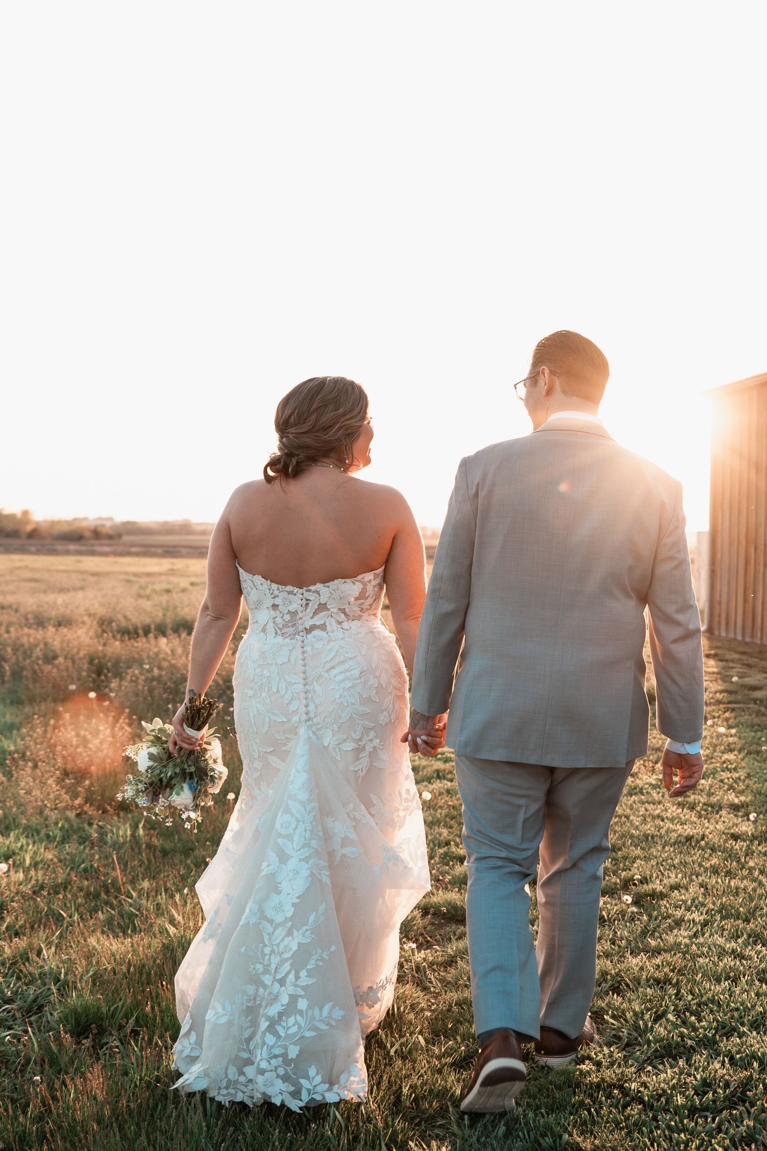 Joyful wedding couple celebrating in a countryside field surrounded by tall grass