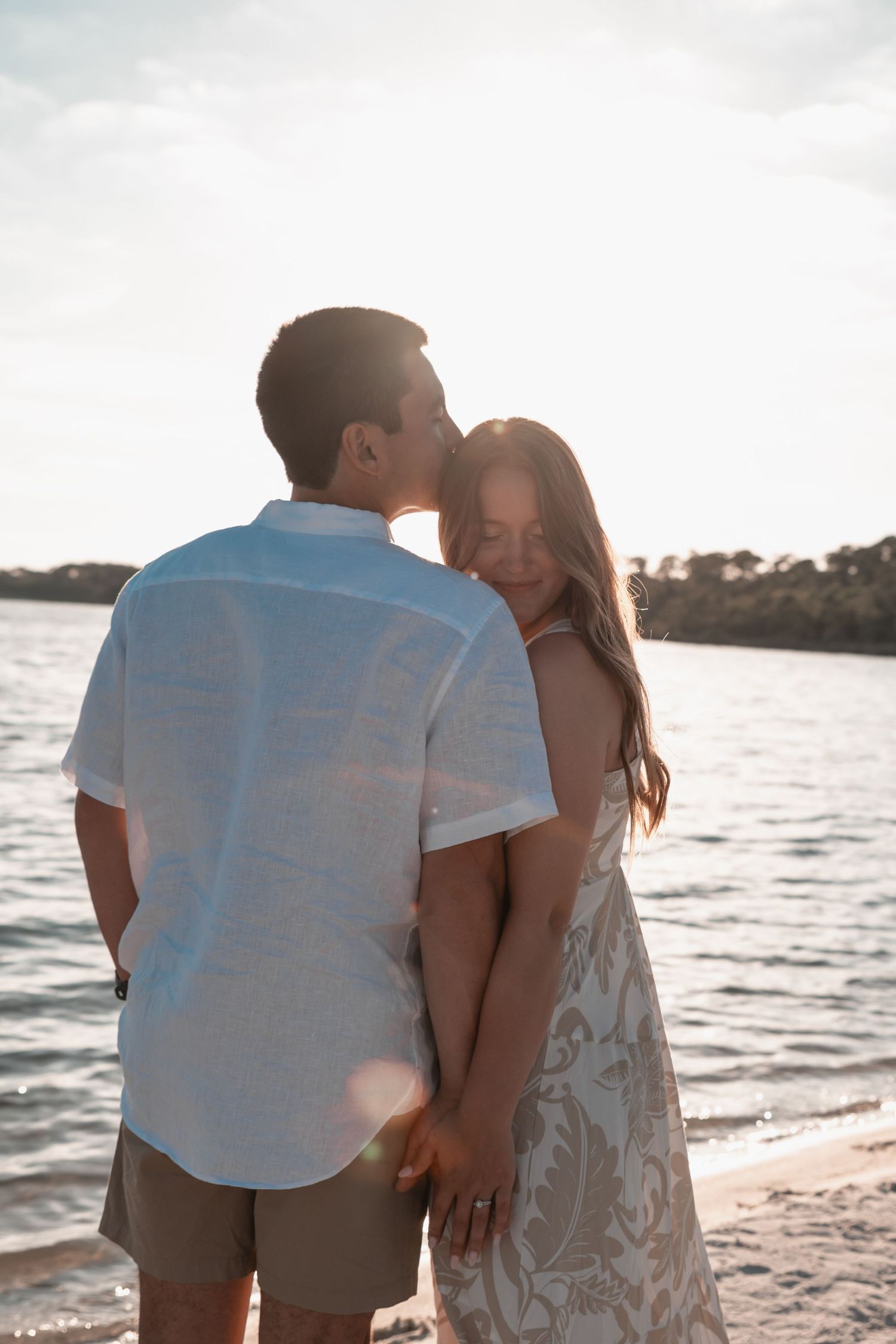 Romantic coastal engagement portrait of a young couple at sunset on the beach