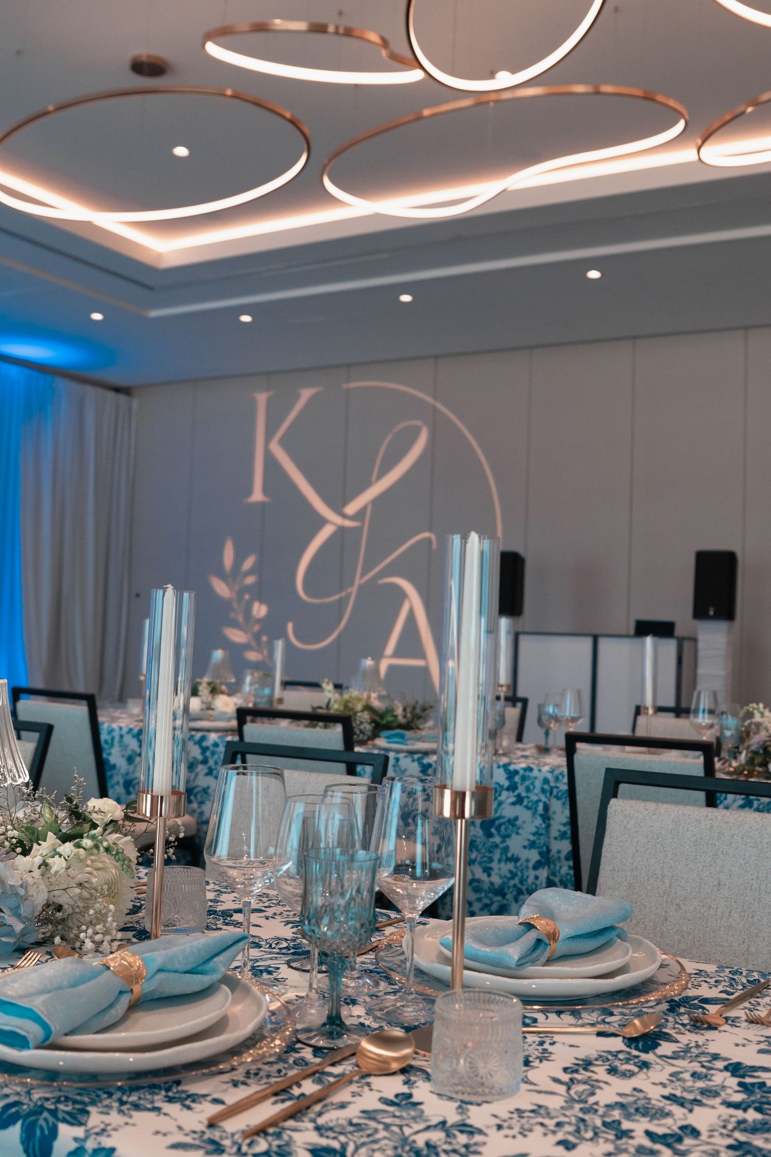 Elegant blue and white wedding reception table with monogram K&A projection.
