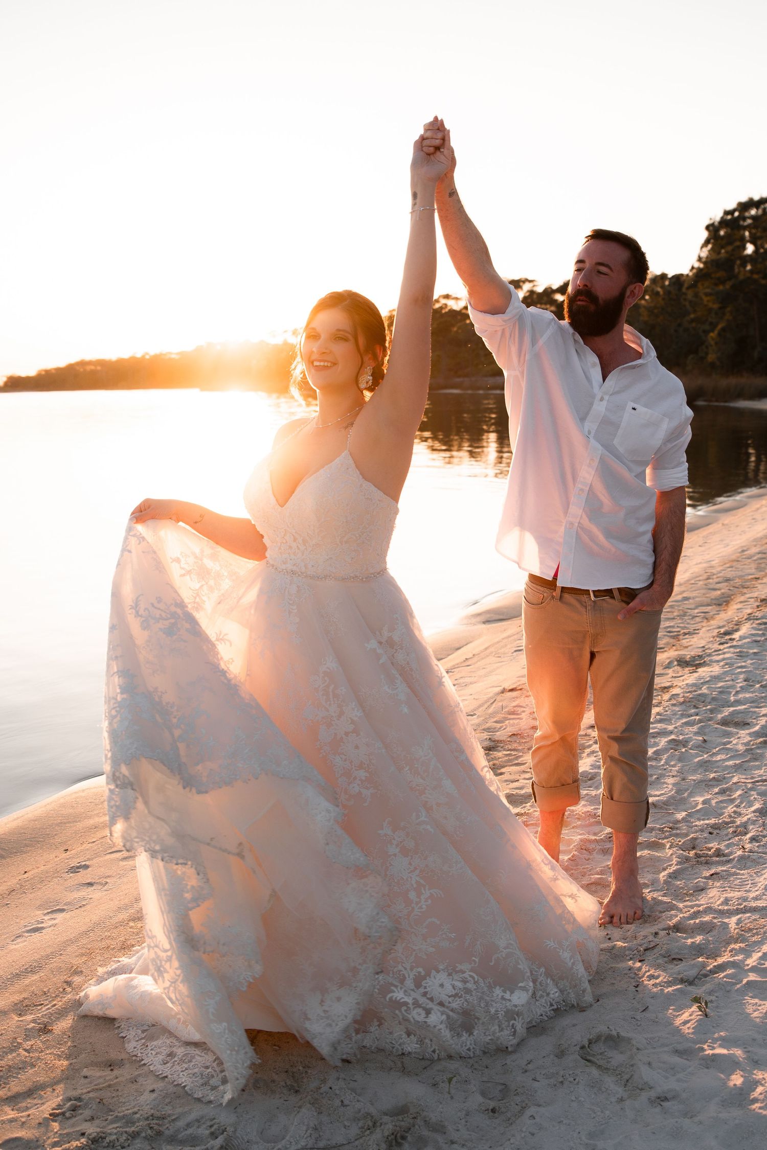 Cinematic beach wedding portrait of couple walking along the water at sunset