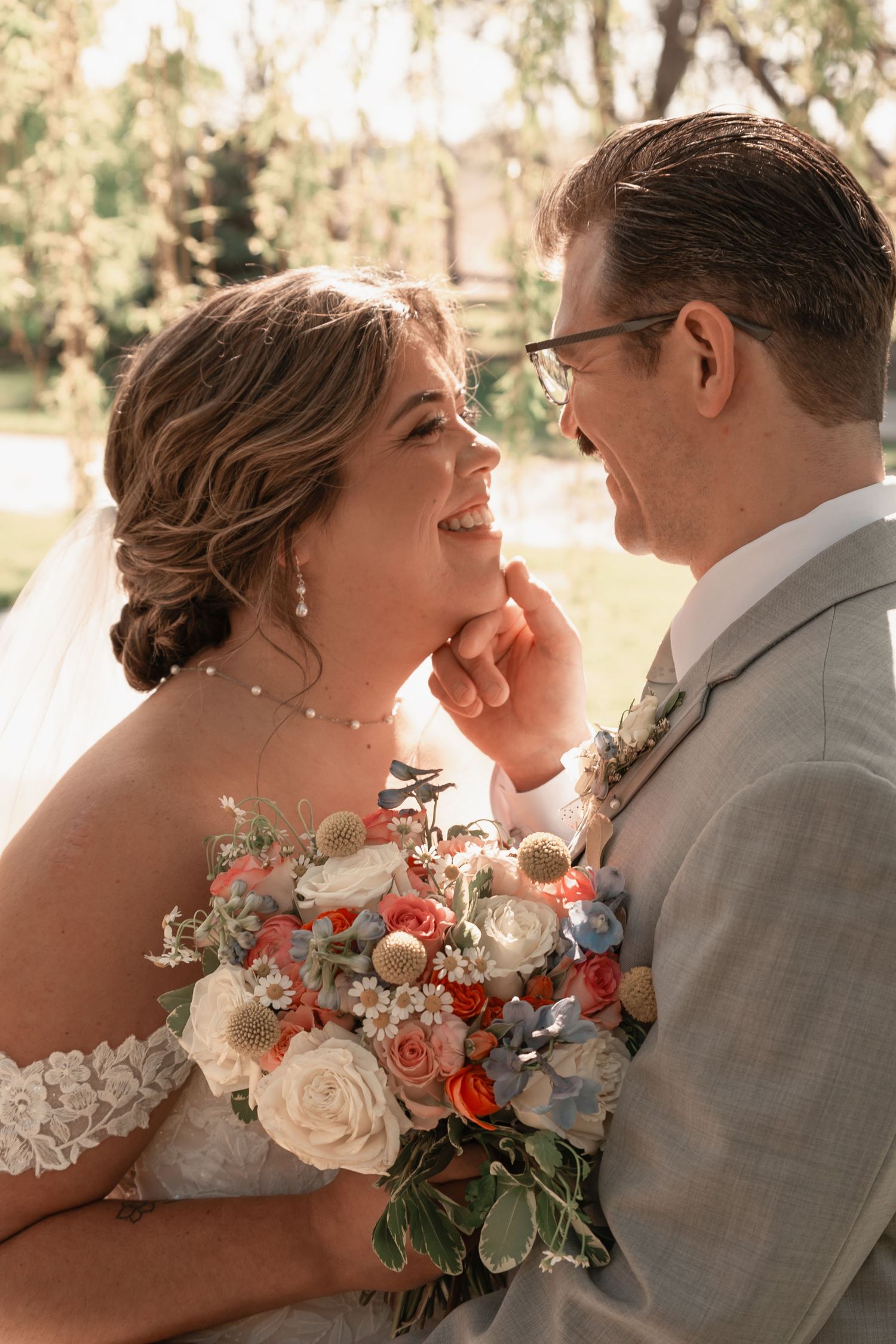 Joyful bride and groom share an intimate moment holding a vibrant floral bouquet.