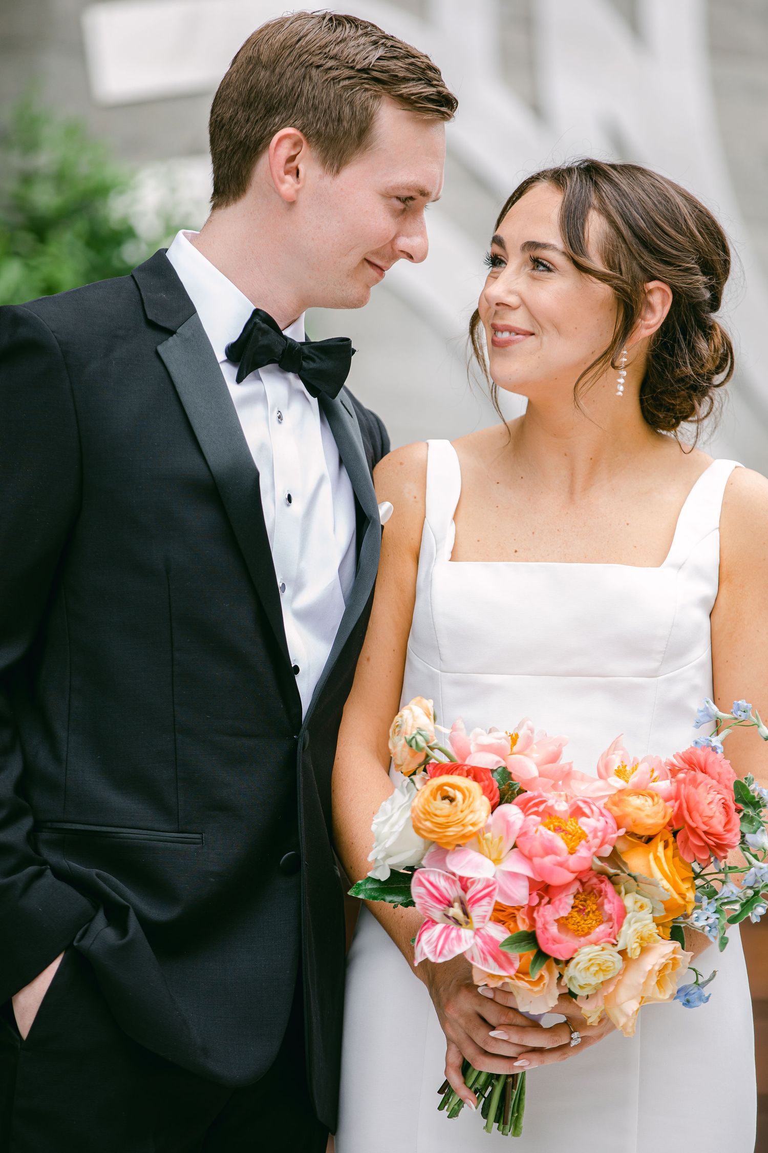 Bride with colorful pastel floral bouquet and groom in classic black tux