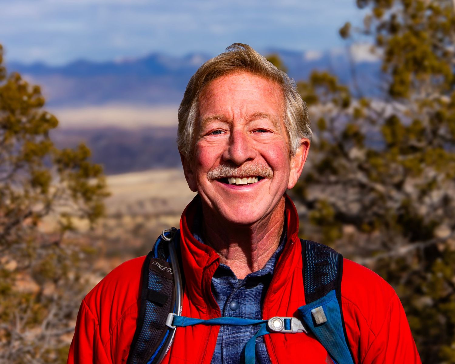 A pet portrait photo of a man in a red jacket smiling for the website WhiteFlamingoPhotos.com