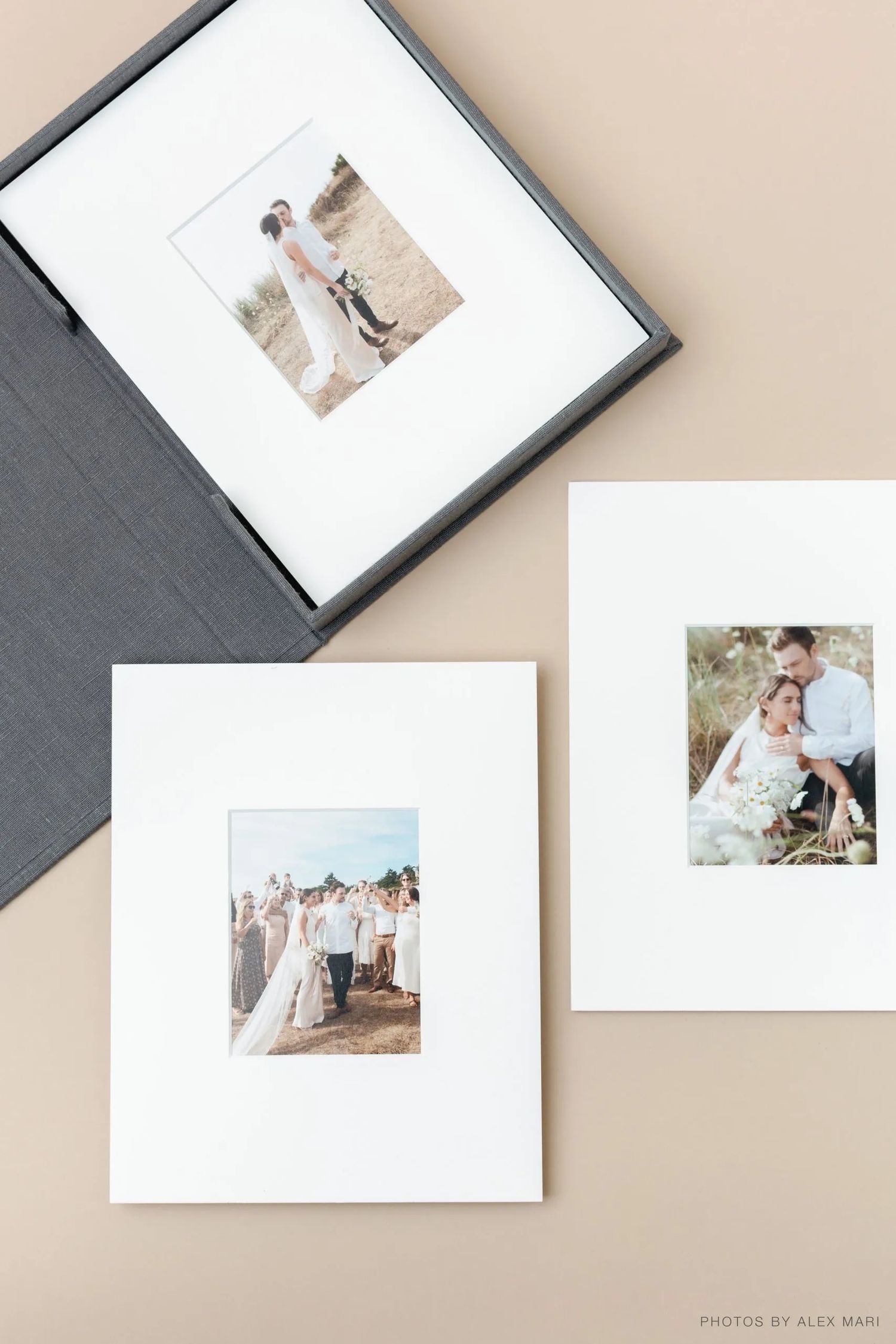 Wedding photographs displayed in elegant white matting and black frames arranged on a neutral beige surface.