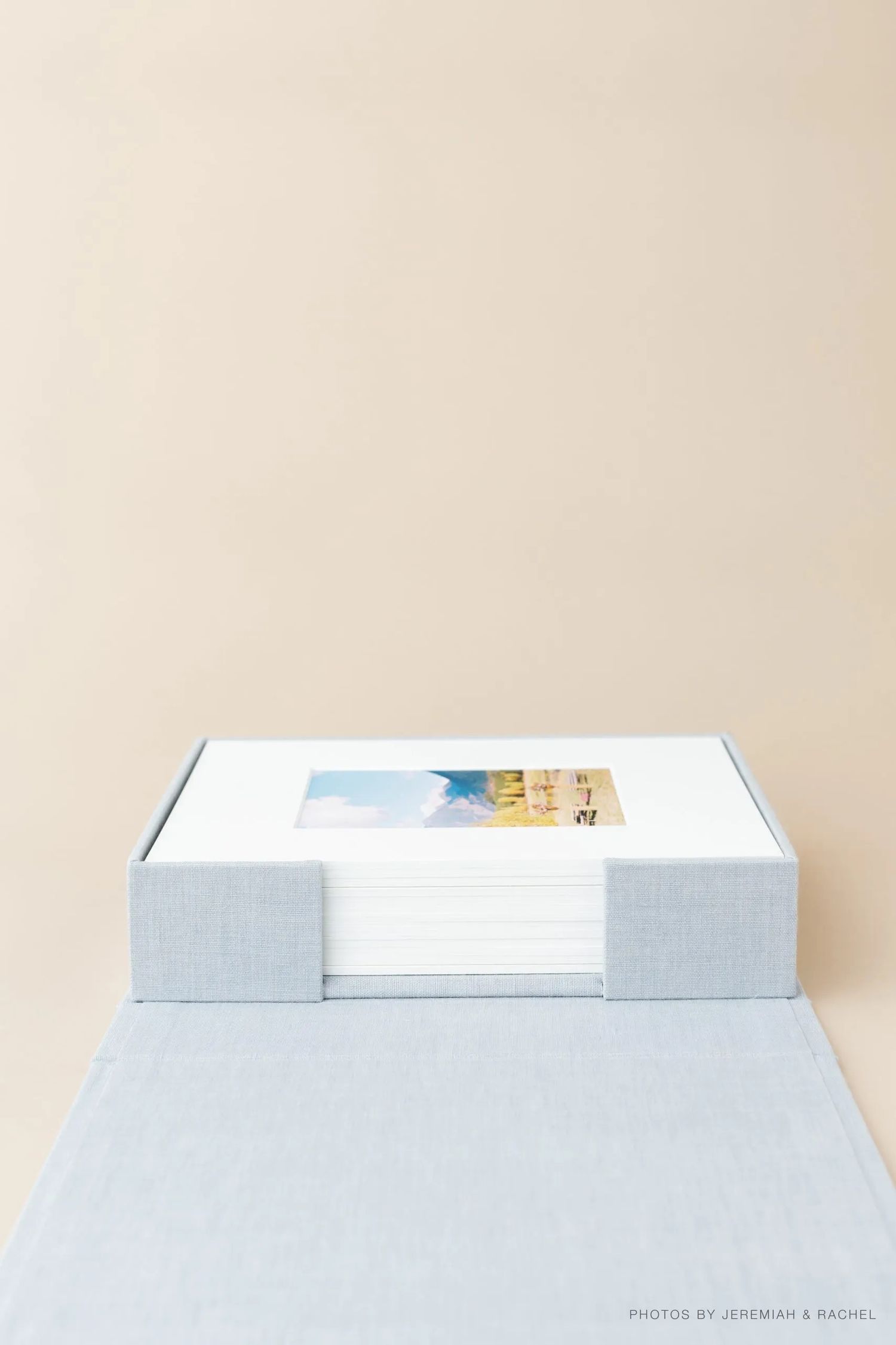 A white rectangular box with a small photograph set in the center against a beige background.