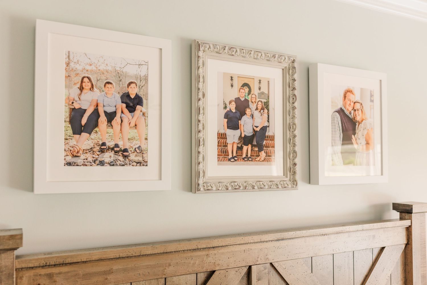 A white-painted media console set against a wall decorated with framed family portraits and photographs.