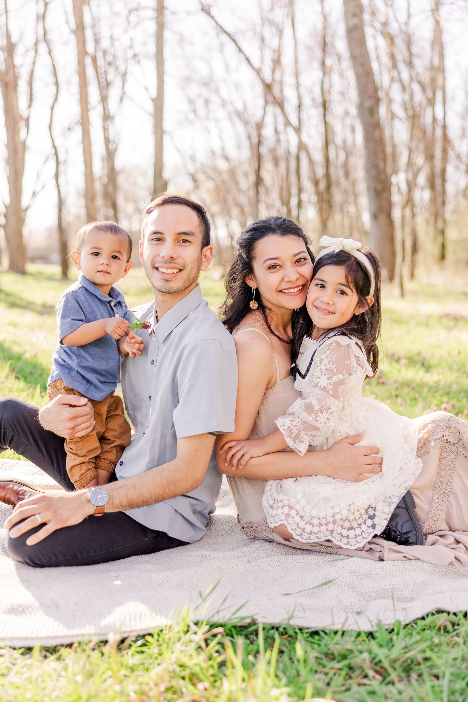 Family relaxing together on a blanket outdoors in nature during spring.