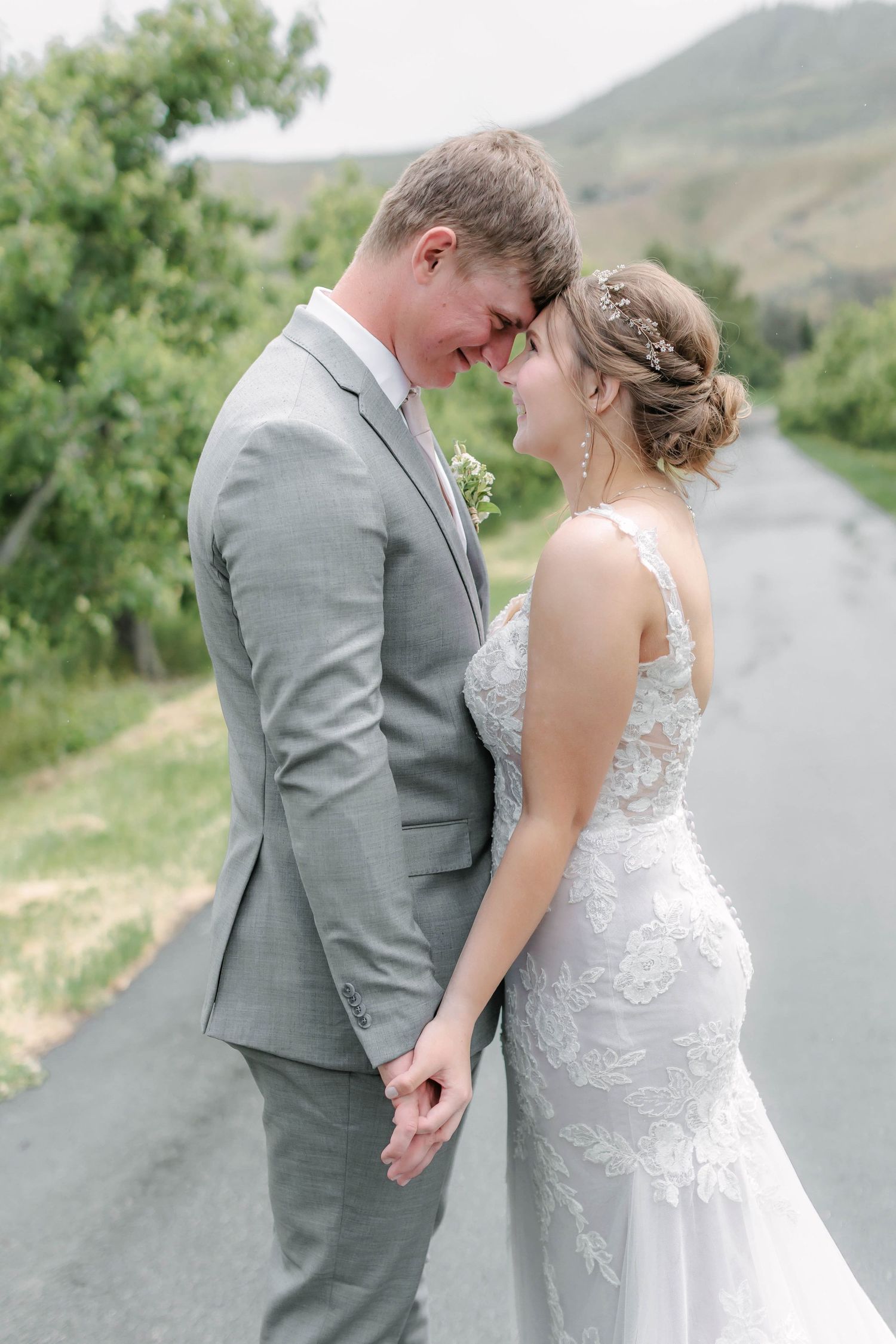 Romantic wedding photos captured on a mountain road with lush greenery in the background.