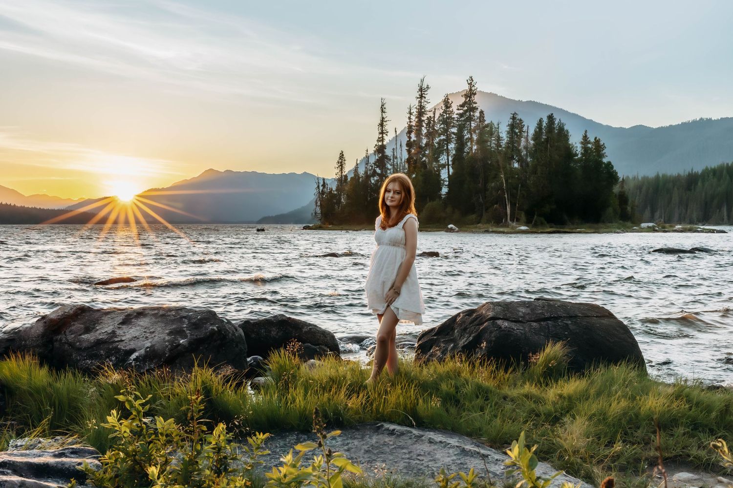 Silhouette of person in white dress against dramatic mountain sunset.