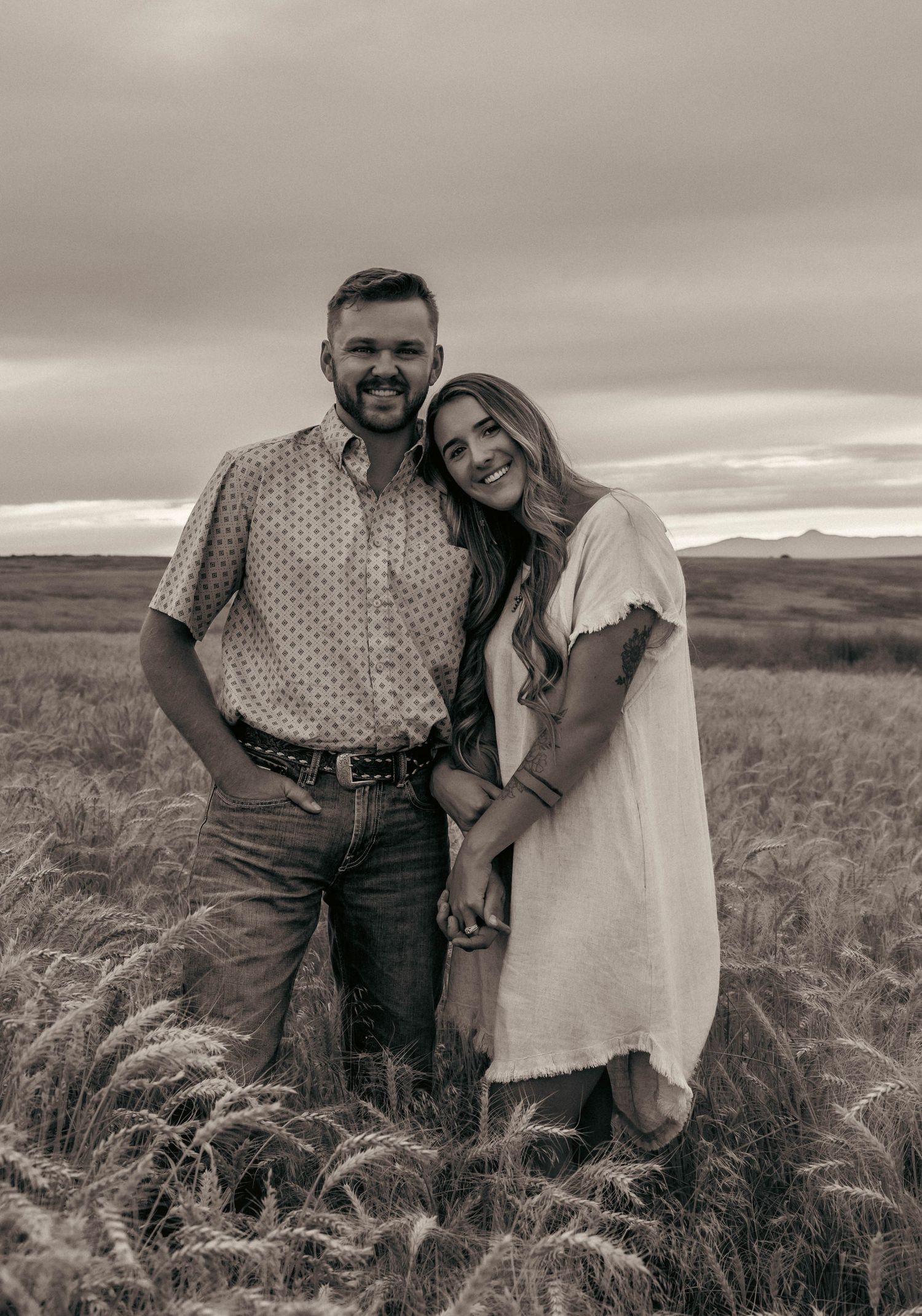 Romantic couple portrait in wheat field during golden hour in black and white.