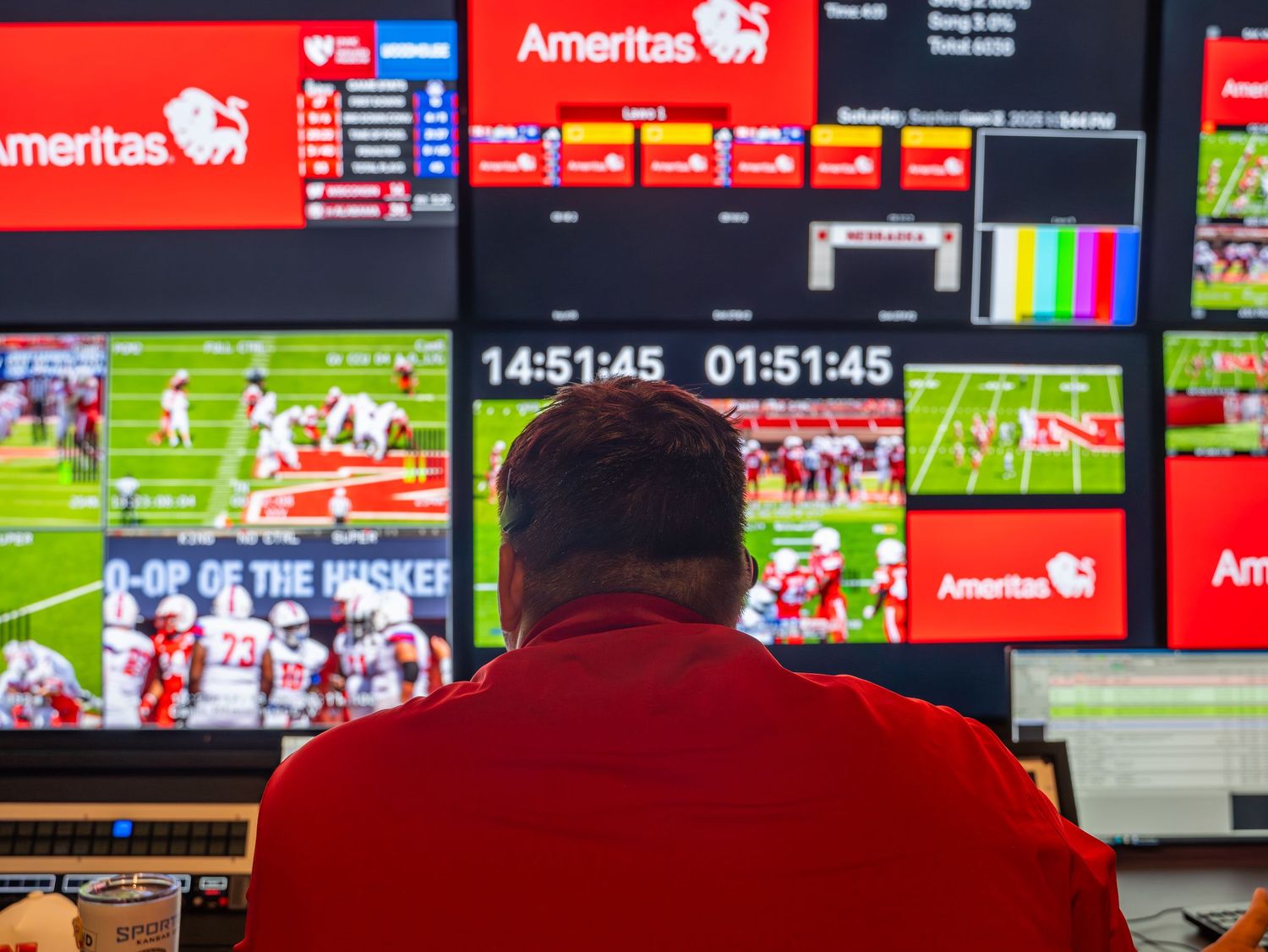 Multiple TV screens showing live sports coverage with Ameritas branding visible in a control room or broadcast setting.