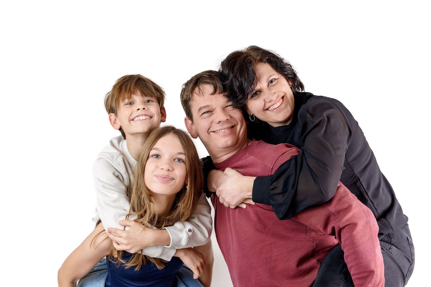 A happy family group poses together while embracing and smiling at the camera against a white background.