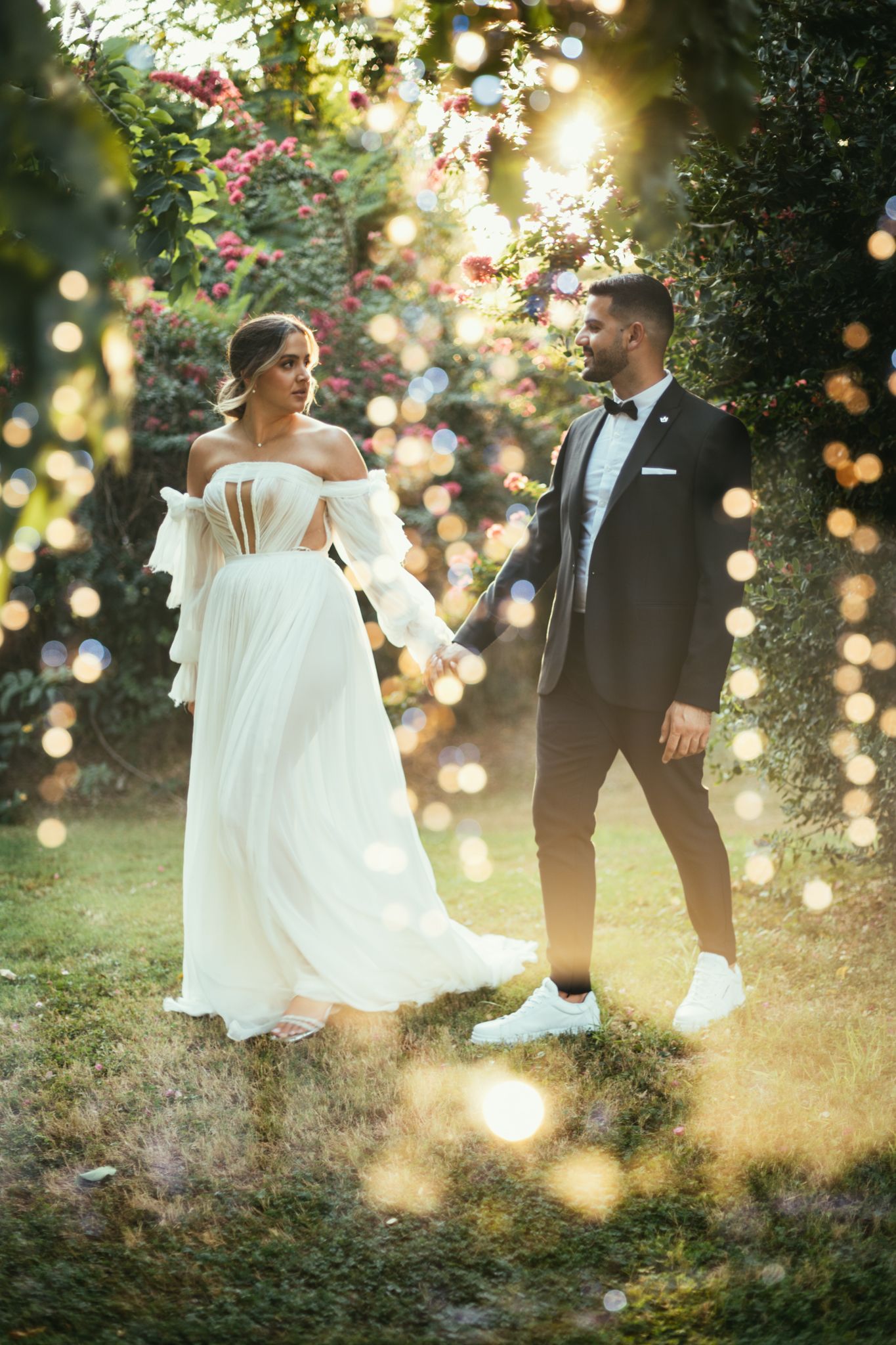 Romantic garden wedding portrait with magical bokeh lighting effects at sunset.