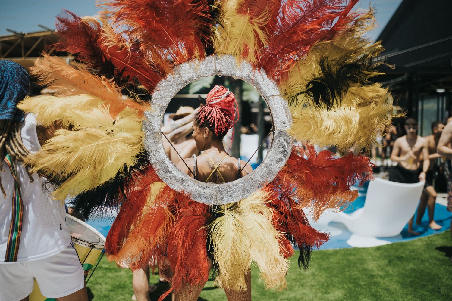 Colorful feathered headdress with mirror detail displayed at outdoor festival.
