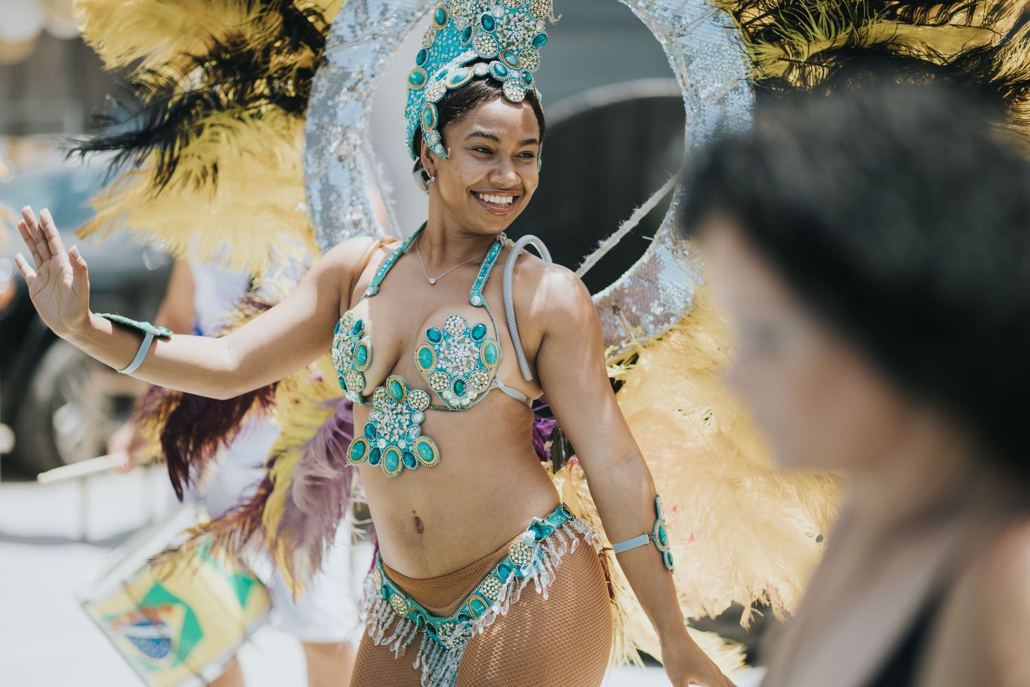Carnival dancer in turquoise costume performing at festival celebration.