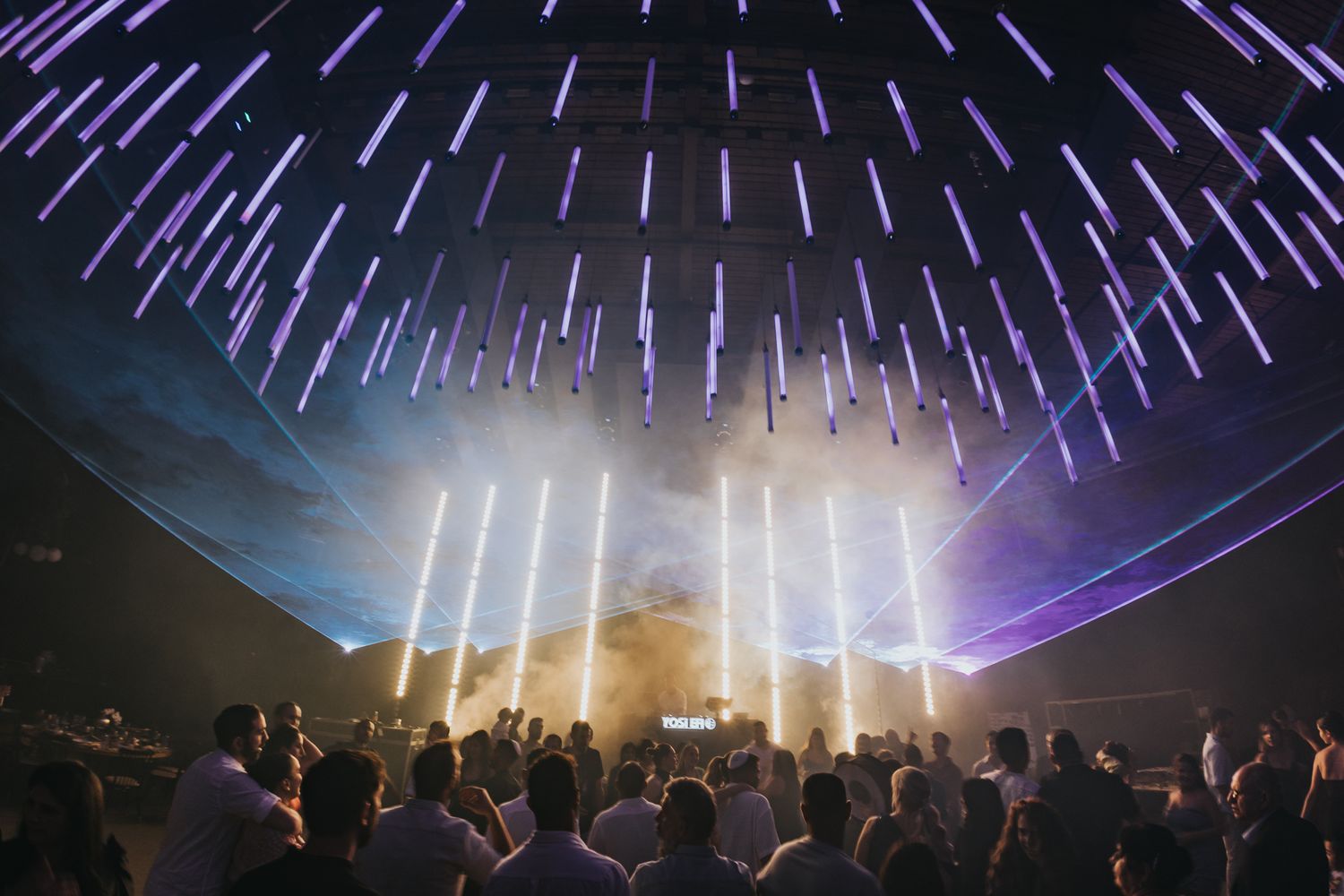 Stunning light beam installation creates a dome effect over an energetic event crowd.