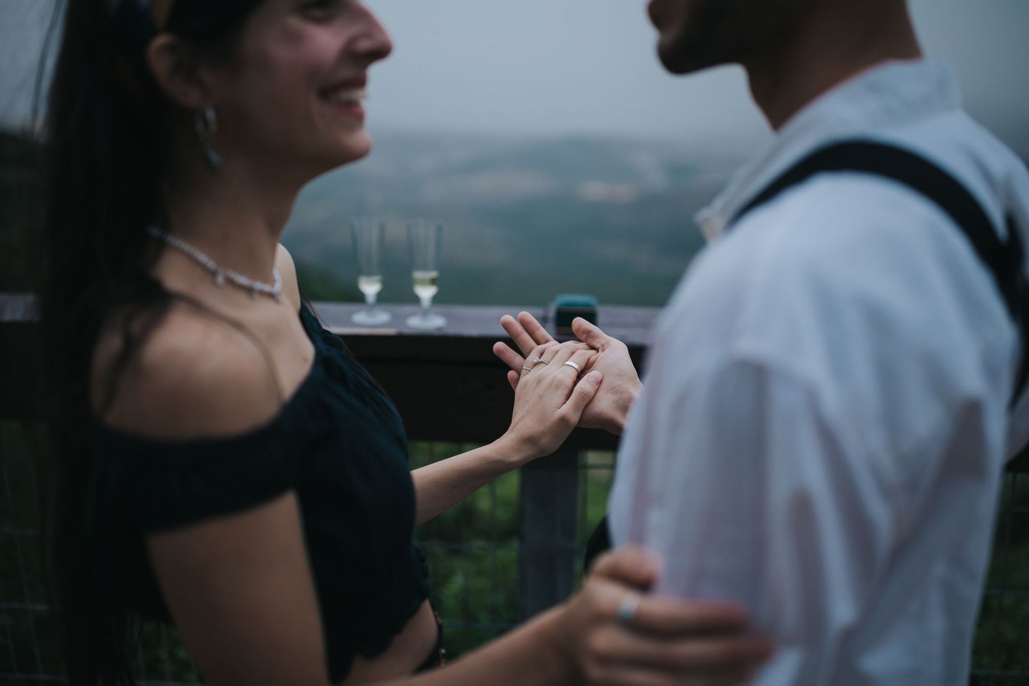 Couple sharing moment with champagne glasses on balcony at dusk.
