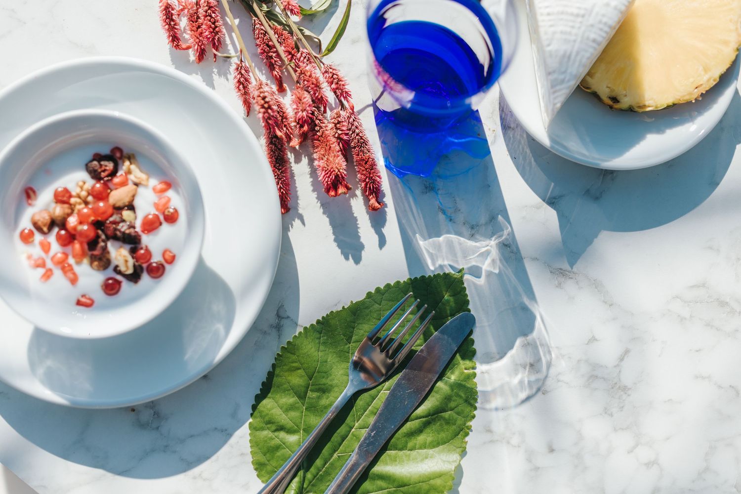 Elegant table setting with blue glassware and fresh ingredients on marble surface.