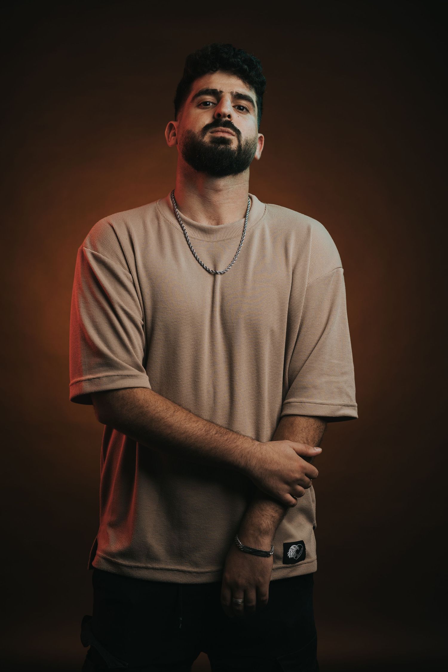 Portrait of person in beige t-shirt against dark background with warm lighting.