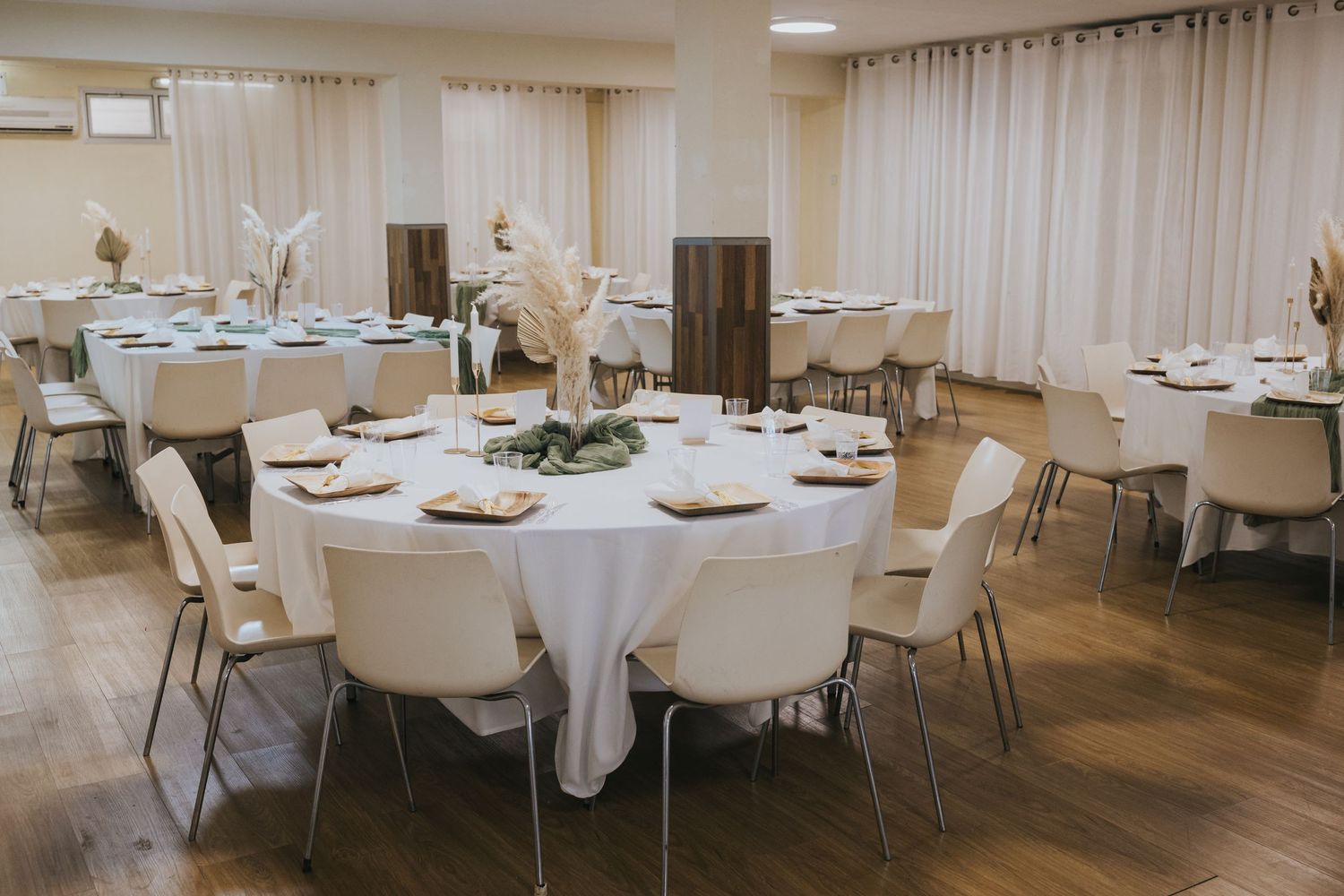 Modern event space set up with round white-clothed tables and chairs for a celebration.
