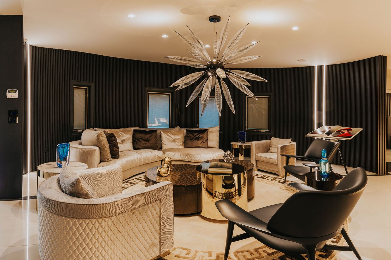 Modern lounge area with starburst chandelier, curved sofa, and black accent walls.
