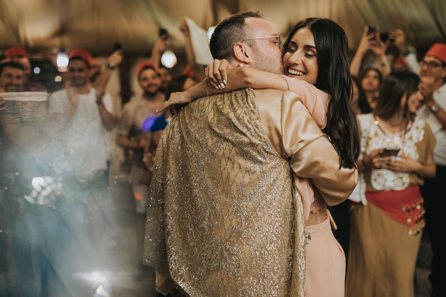 Lively dance moment at reception with sparklers and guests in background.