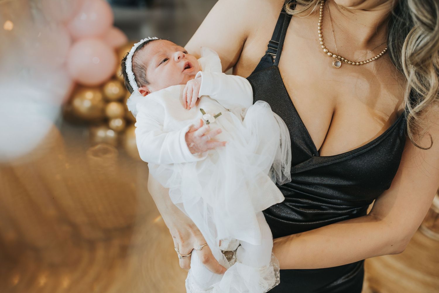 Baby in white christening gown being held during special celebration.