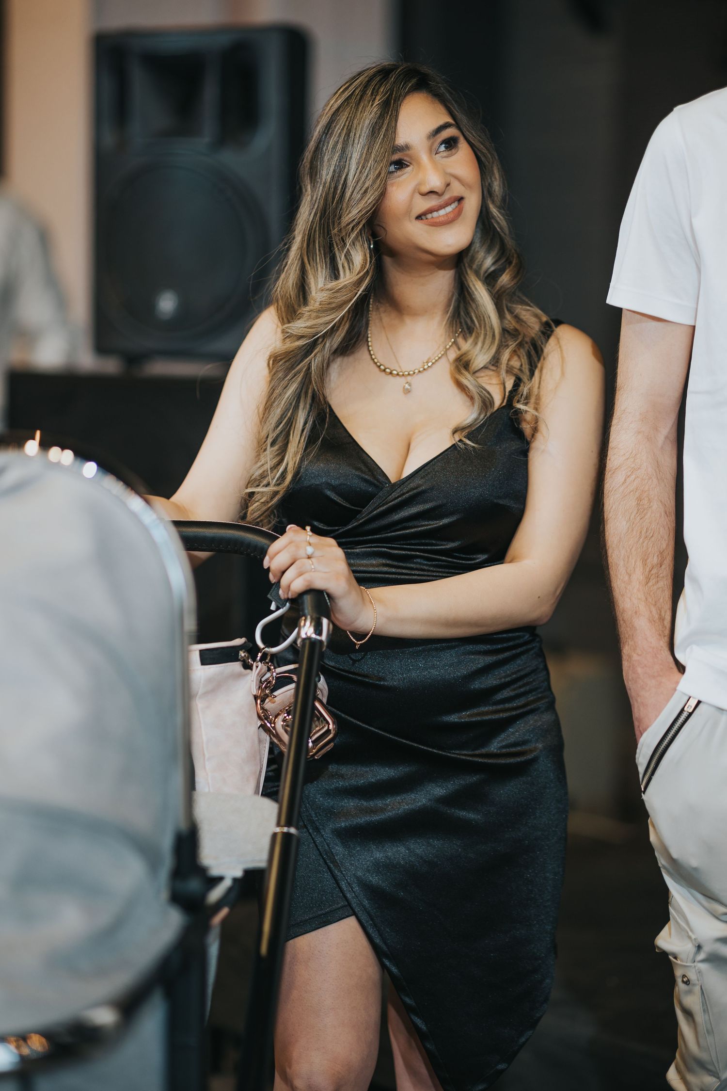 Woman in black formal dress holding traditional decorative objects at celebratory event.