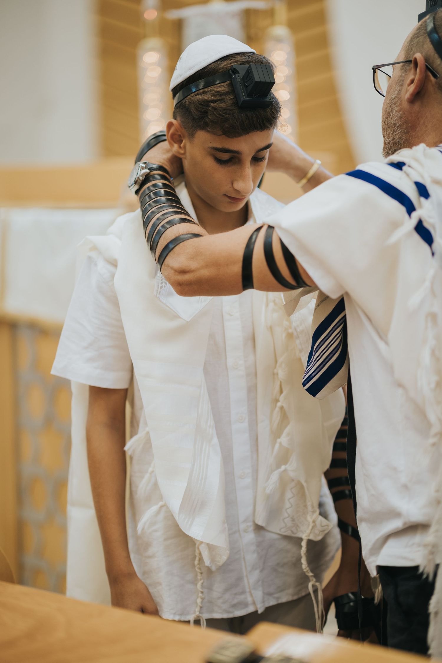 Someone being helped with wrapping tefillin during a religious ceremony.