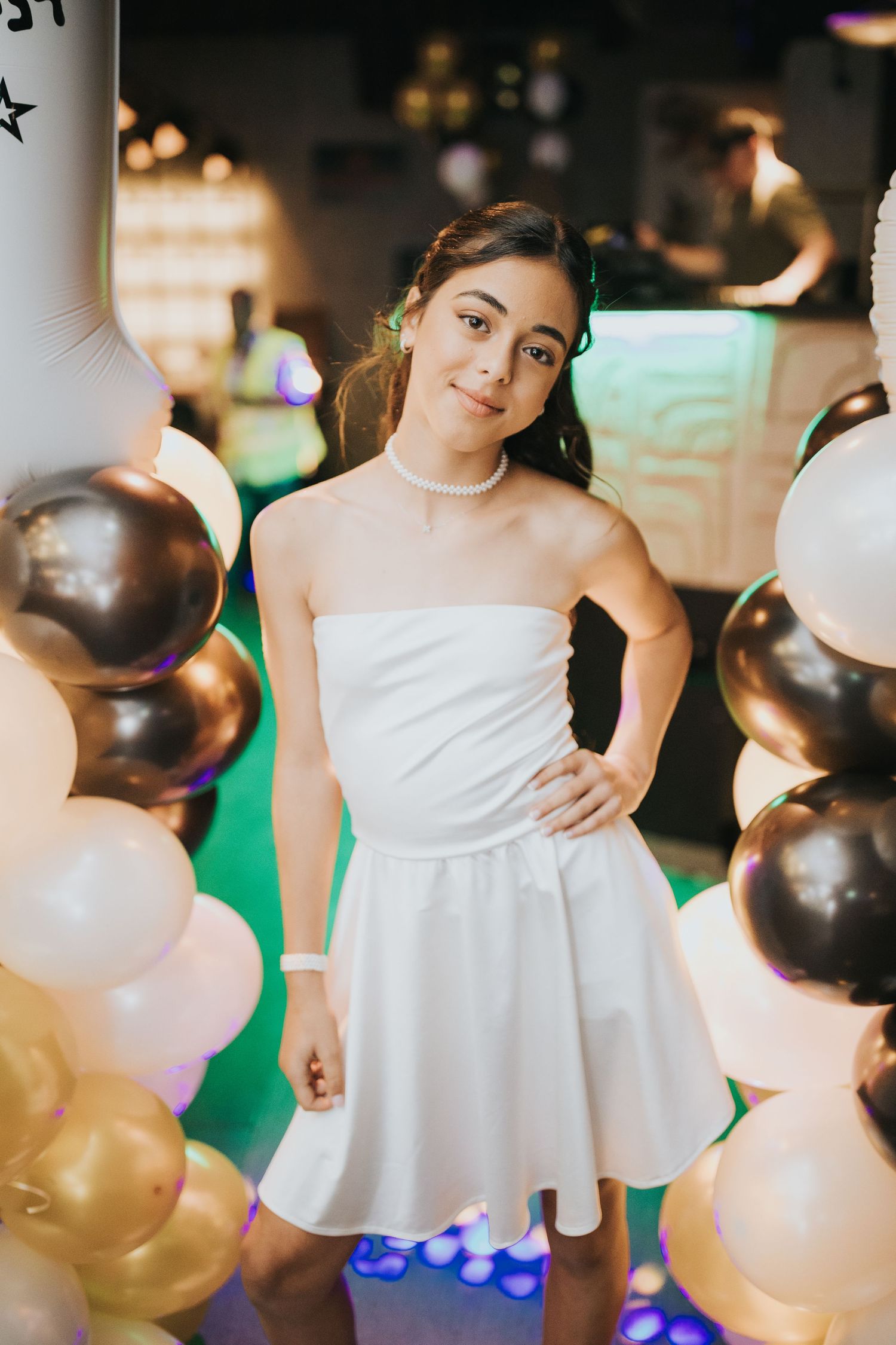 Party portrait with white dress surrounded by gold and white balloons.
