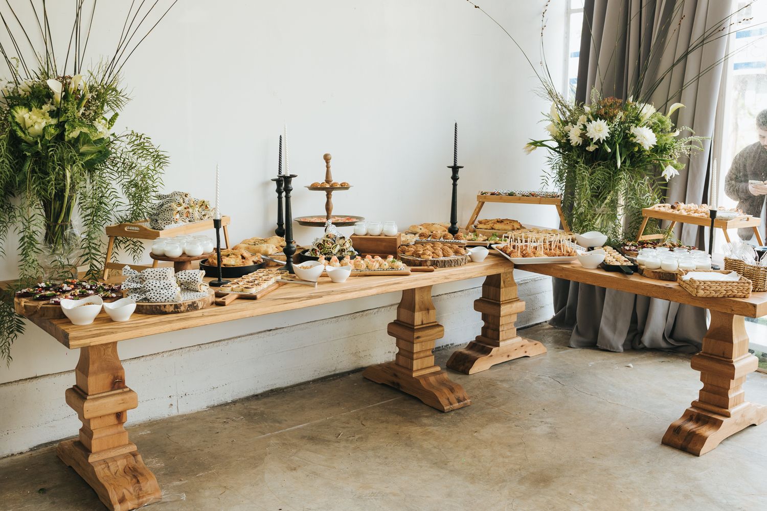 Elegant dessert table with wooden stands displaying pastries and floral arrangements.