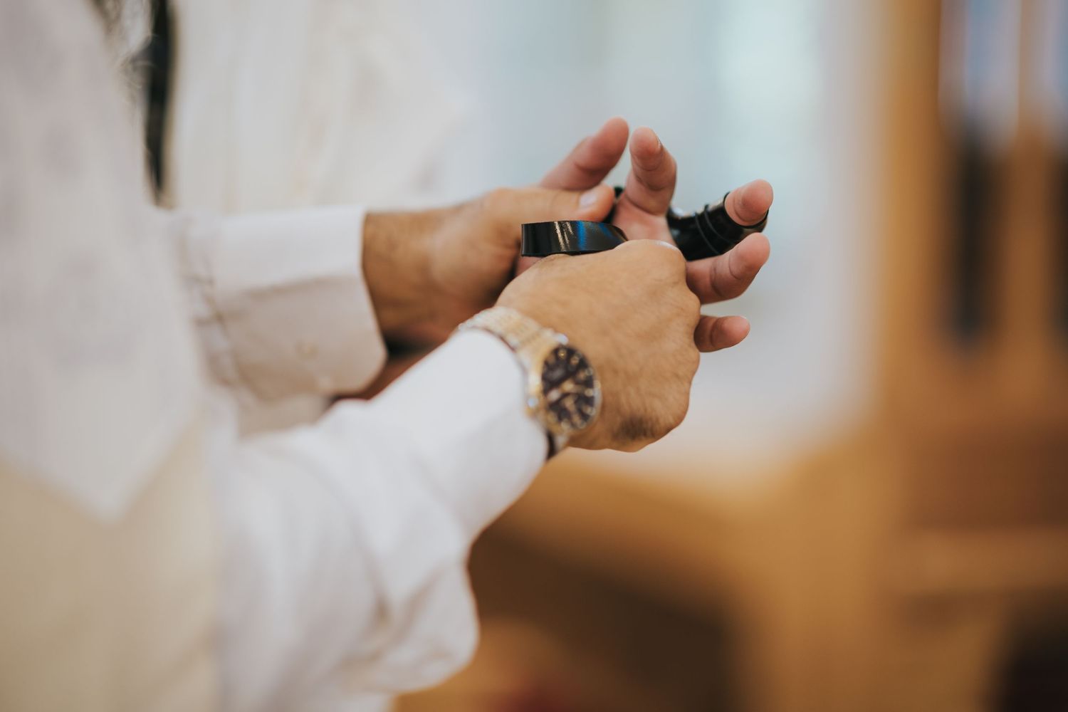 Close-up view of hands wearing tefillin straps during a Jewish prayer ceremony.