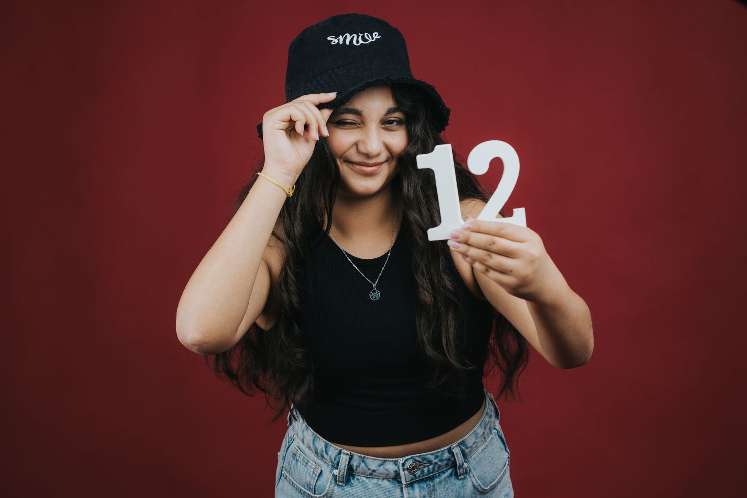 Casual portrait against red background showing number twelve.