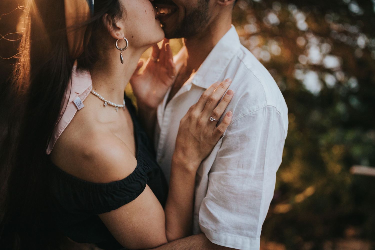 Intimate couple sharing a romantic sunset moment with soft golden lighting.