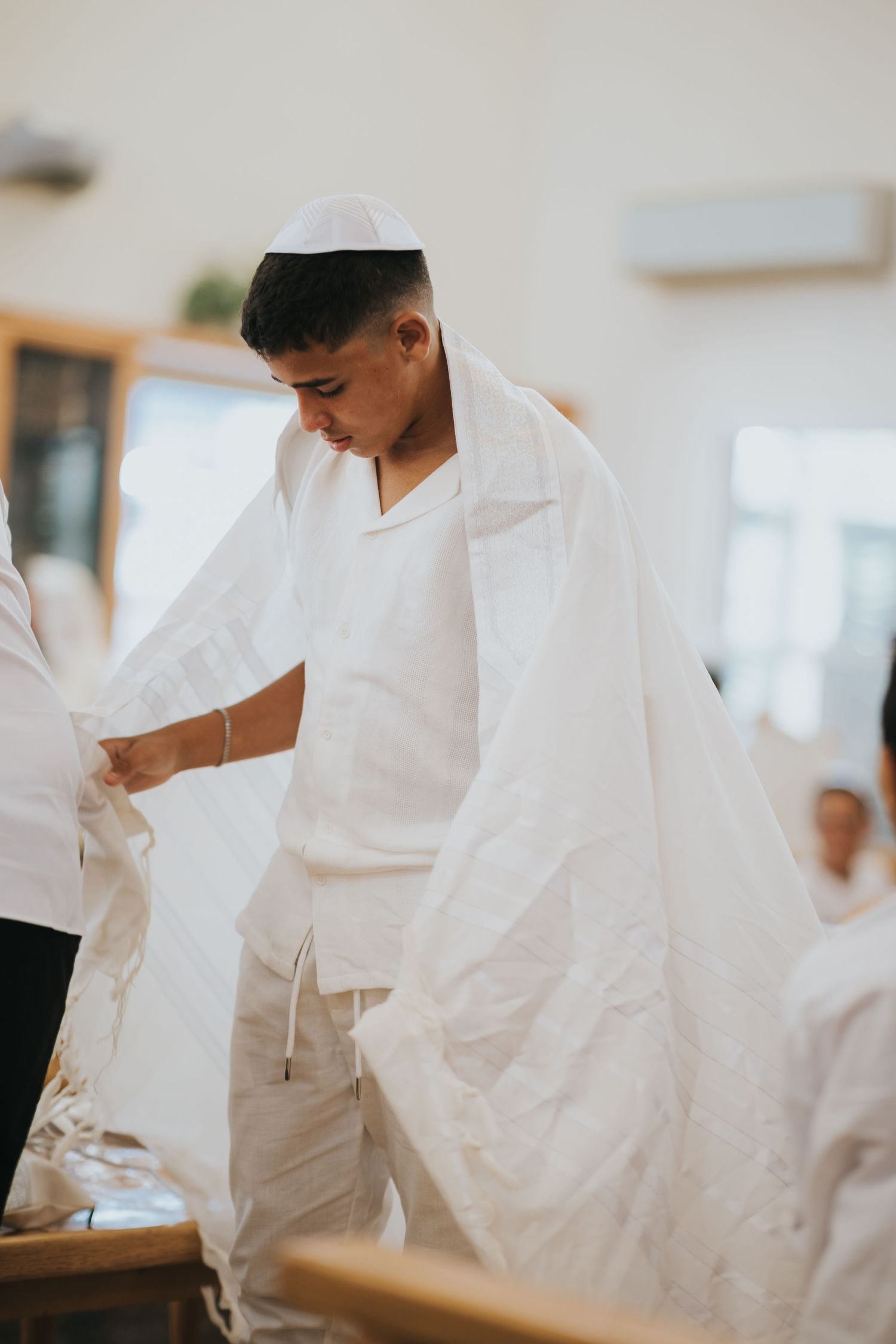 A person in white garments participates in a religious ceremony.