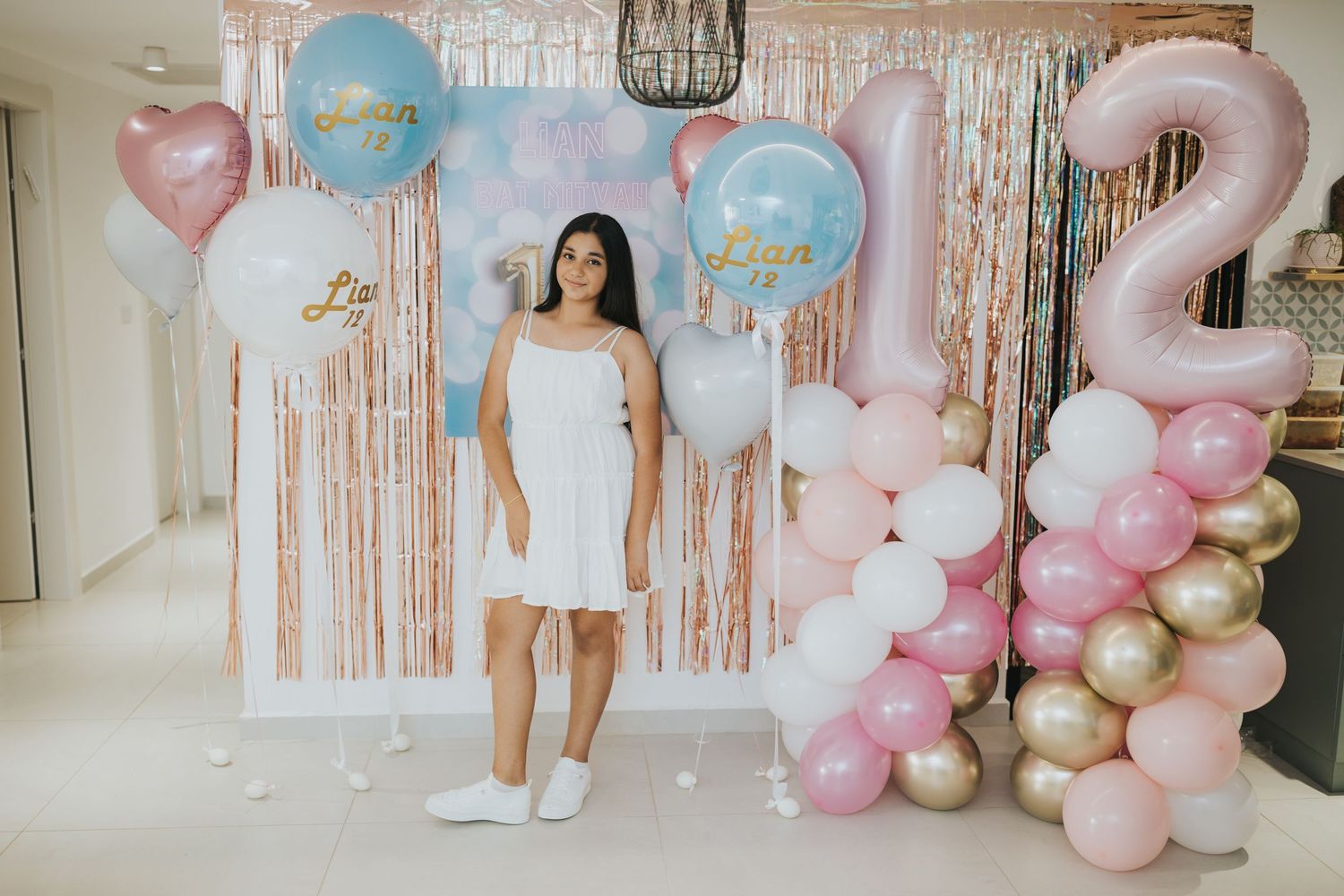 Birthday party setup with pink and blue balloon decorations against a sparkly backdrop.
