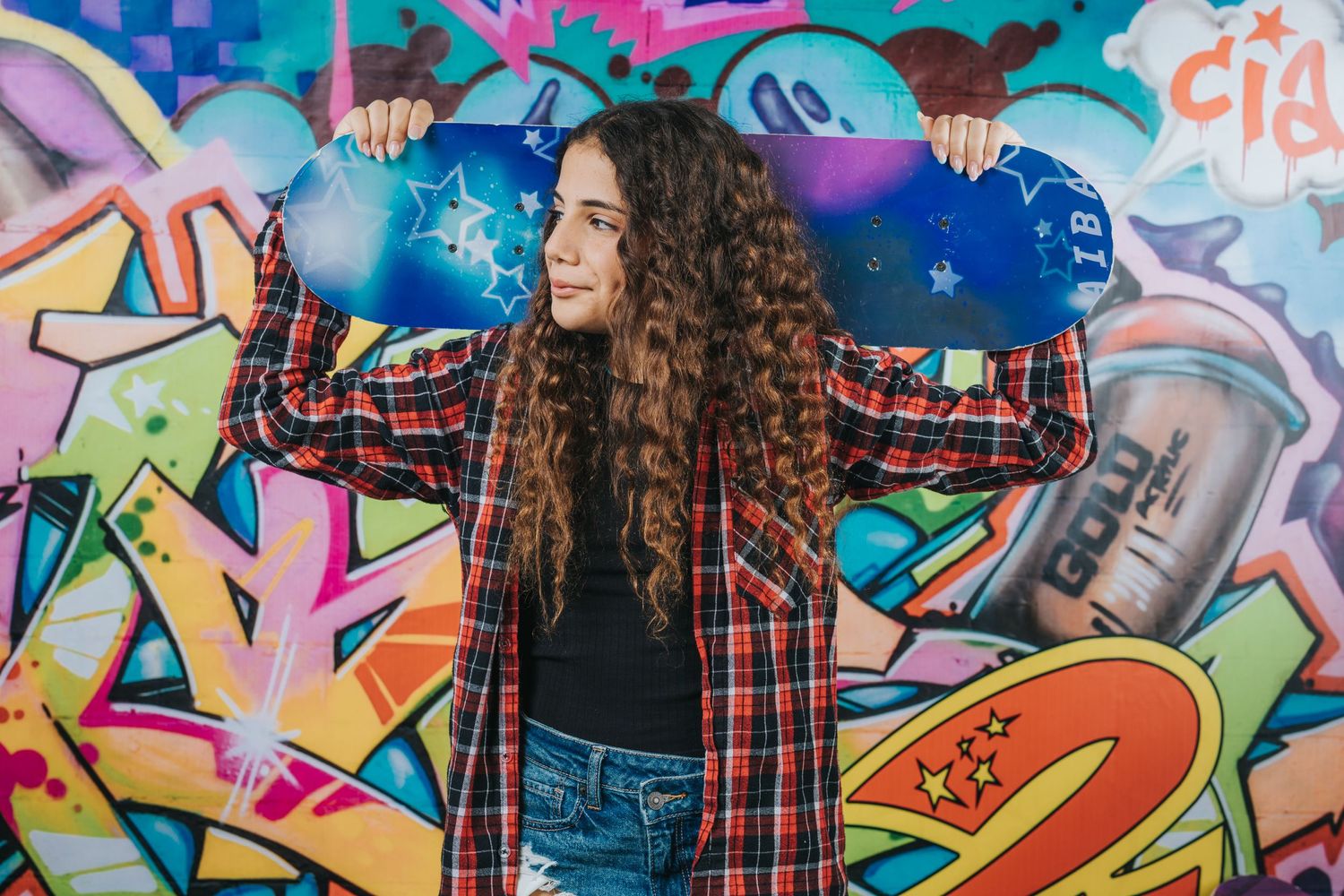 Casual style against colorful graffiti wall wearing plaid shirt and jeans with urban art background.