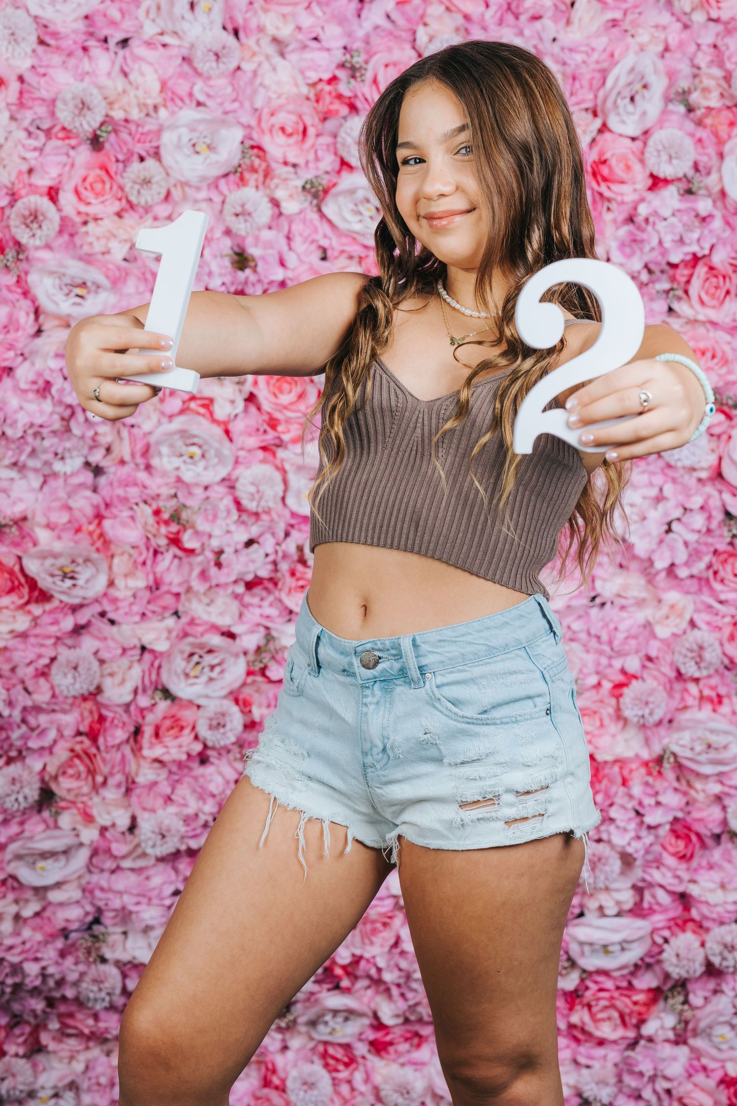 Modern photo shoot against pink floral wall backdrop holding number 12 numerals.