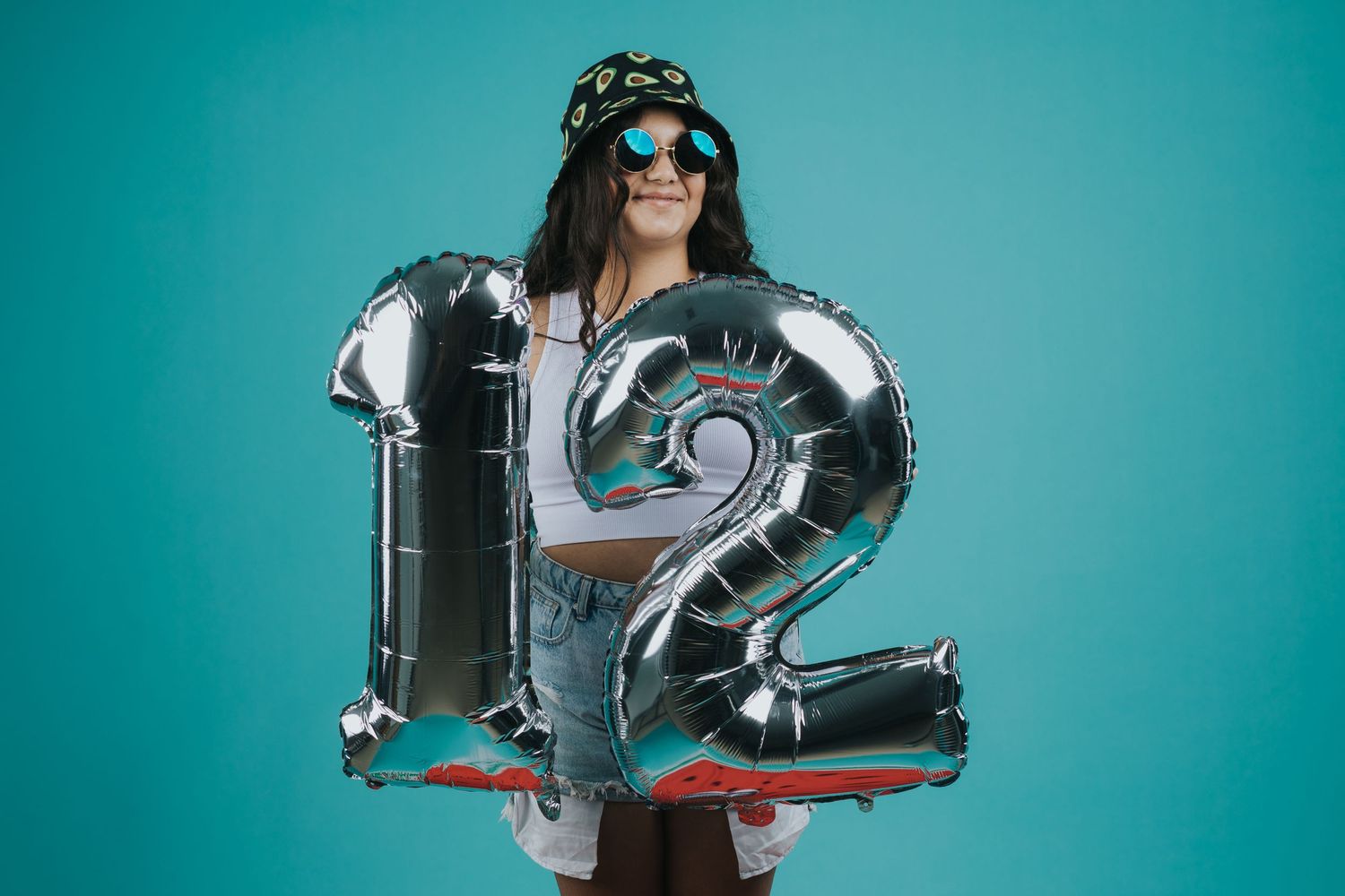 Stylish portrait with silver number 12 balloons against turquoise background.