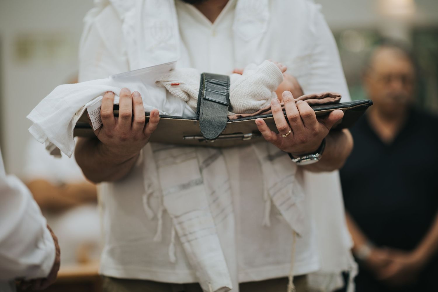 Person in white clothing holding an antique silver ceremonial knife or sword.