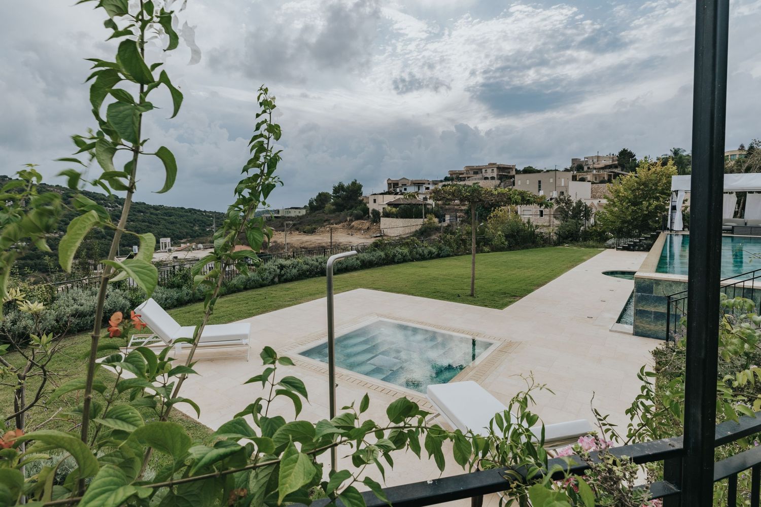 Modern luxury villa with sleek swimming pool and manicured lawn overlooking a Mediterranean hillside landscape.