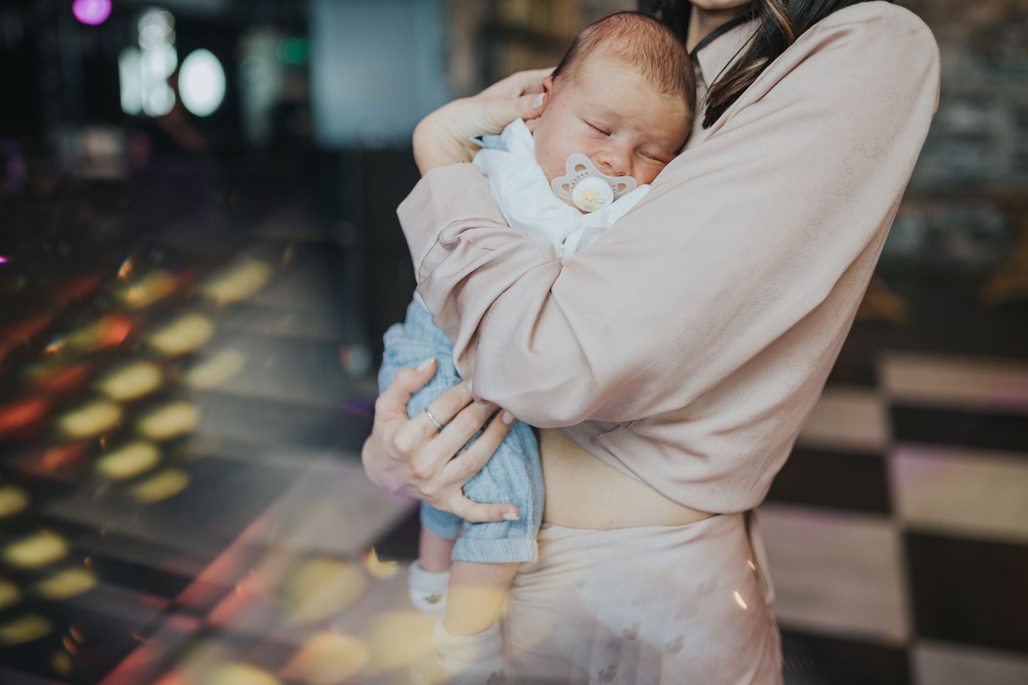 Baby sleeping peacefully in caregiver's arms at celebration venue.