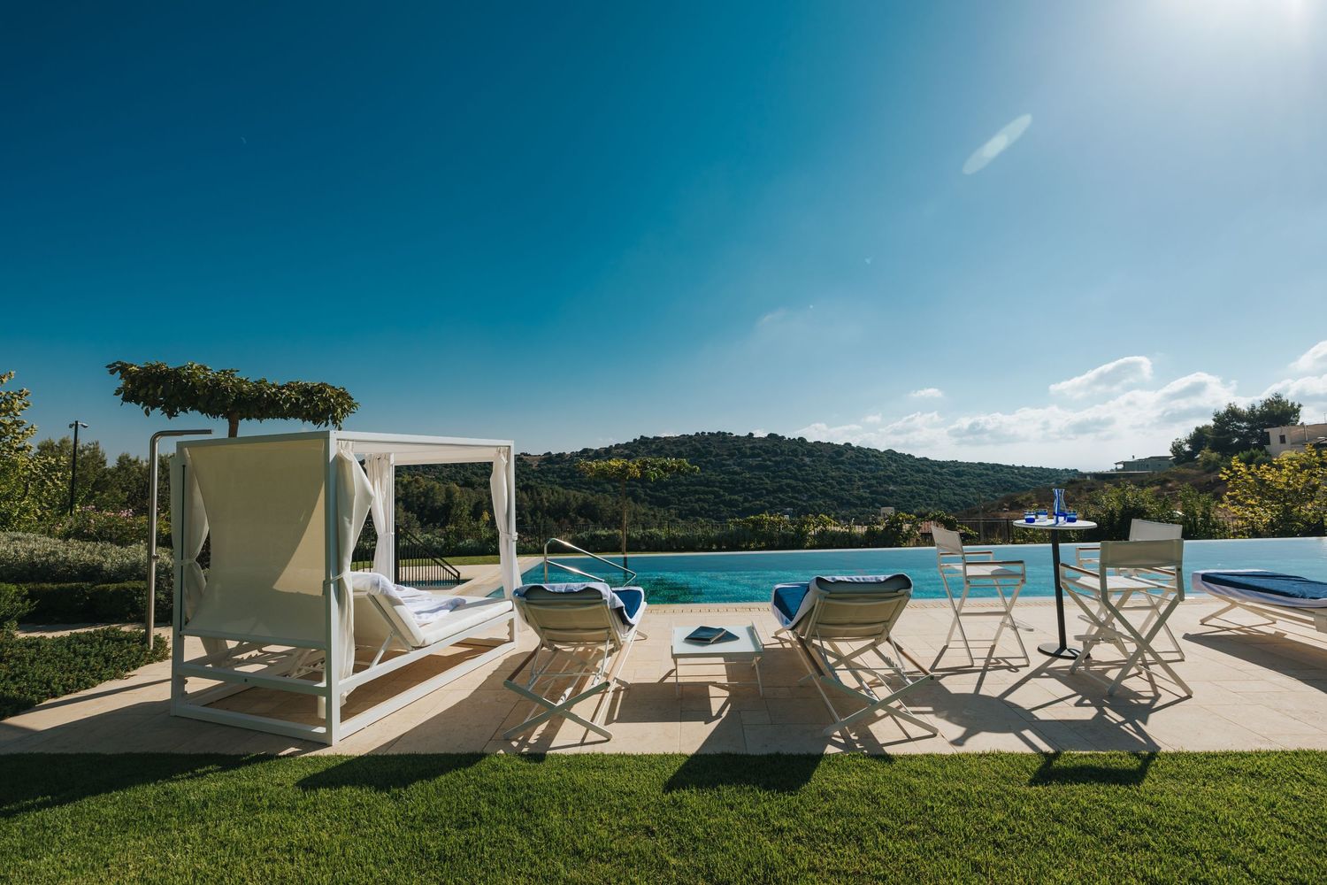 Modern luxury villa pool deck with white loungers and panoramic ocean views.