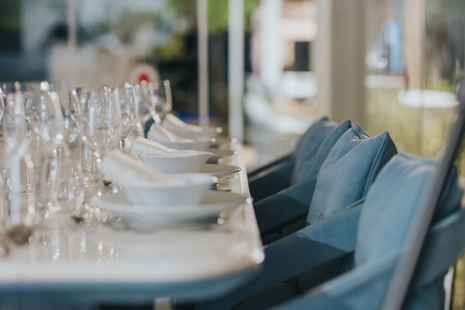Formal dining table setting with white plates and blue velvet chairs in elegant arrangement.