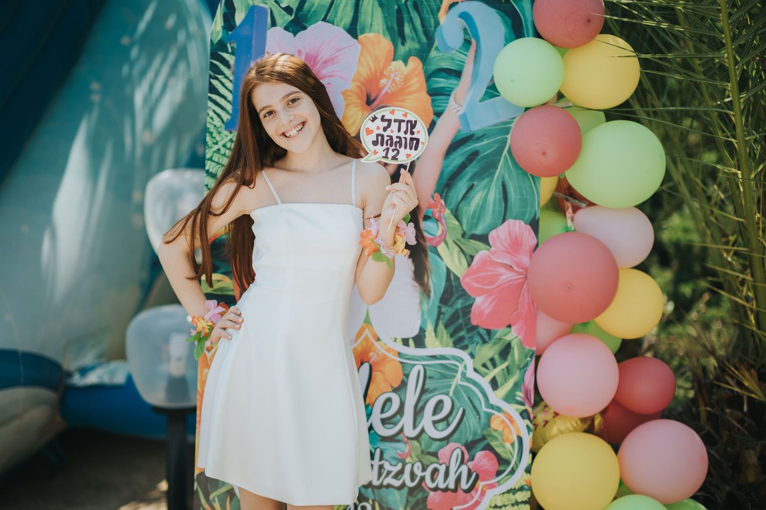 Celebration setup with white dress against tropical-themed balloon display.